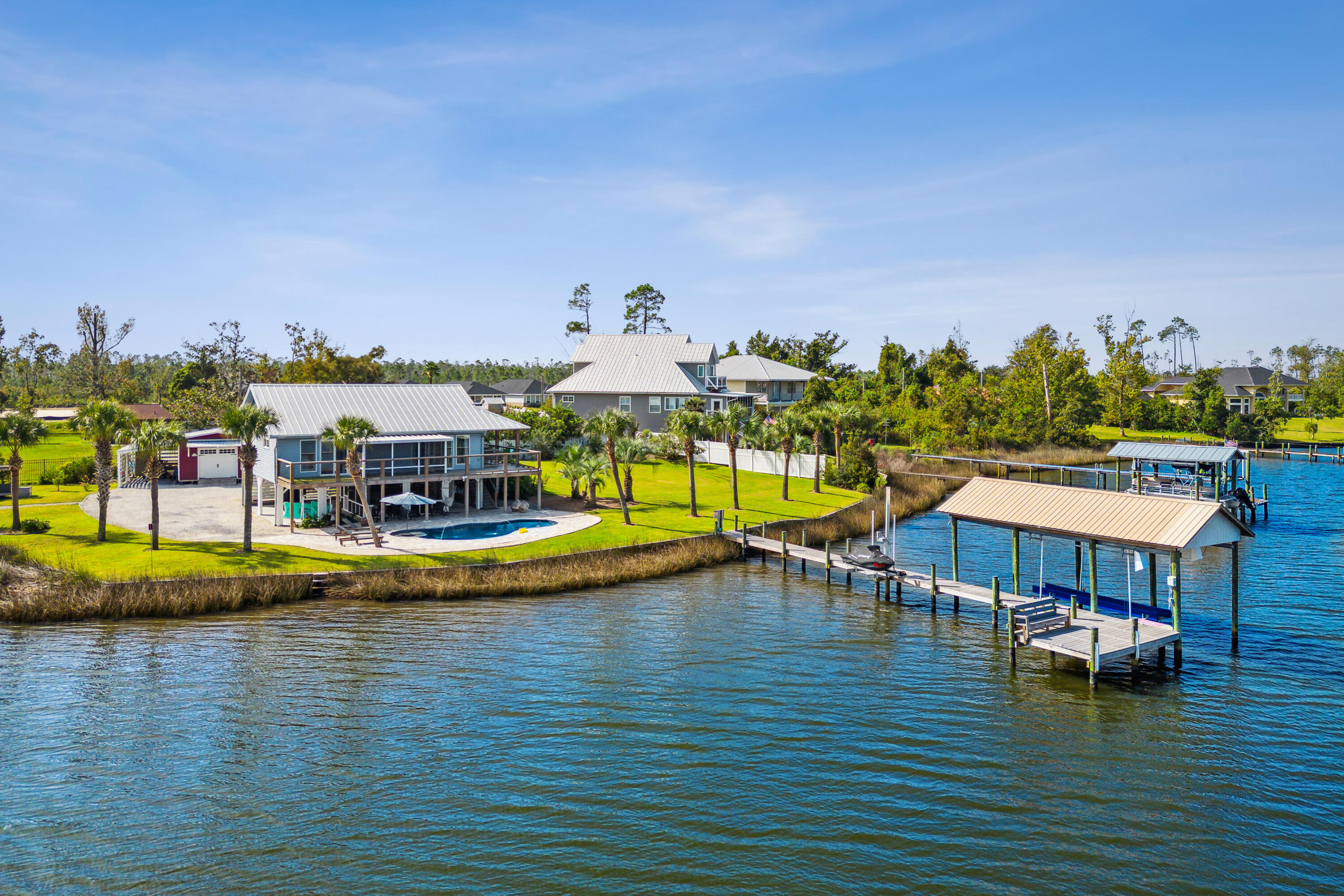Gorgeous waterfront home that's as close to paradise as you can get.  As you enter through your private security gate fresh beautiful landscaping abounds with breathtaking views of the deep waters of Cook Bayou and East Bay. Along with the views is your own private salt water pool that adds a spa like serenity to this little piece of paradise.  Entering the home, you will immediately notice the bright open floor plan of the living room, kitchen and dining area. The soft wall colors, natural light and beautiful tongue in groove ceilings create a relaxing environment that makes this cozy home feel comfortable and inviting.  Prepare your meals in the beautiful, as well as functional kitchen while admiring your waterfront view.  The large primary bedroom has sliding glass doors that lead out to the balcony and screened in porch that overlooks the bay and pool. The primary bathroom will take your breath away with its spa like feel, with glass walls, double vanity, and tiled shower. On the way to the dock, you will find the recently added 12,000 gallon salt water heated pool with water feature and LED lights. Continue down the composite wood dock to find the covered boat lift with electric motors and a newly installed jet ski lift. Imagine ending your day relaxing on the custom-built bench at the end of the dock watching the dolphins play and birds feed as the sun sets and delivers an unimagined beauty. Every upgrade in this home was carefully thought out and designed for efficiency, functionality, and energy savings from the seamed metal roof to the Bosch air conditioning system. Large oversized work shop with electricity and a lean-to on both sides is great for the hobbyist or craft enthusiast. If you're looking for beautiful property that provides amazing access to water sports and some of the most stunning sunsets around, then you have found it.
