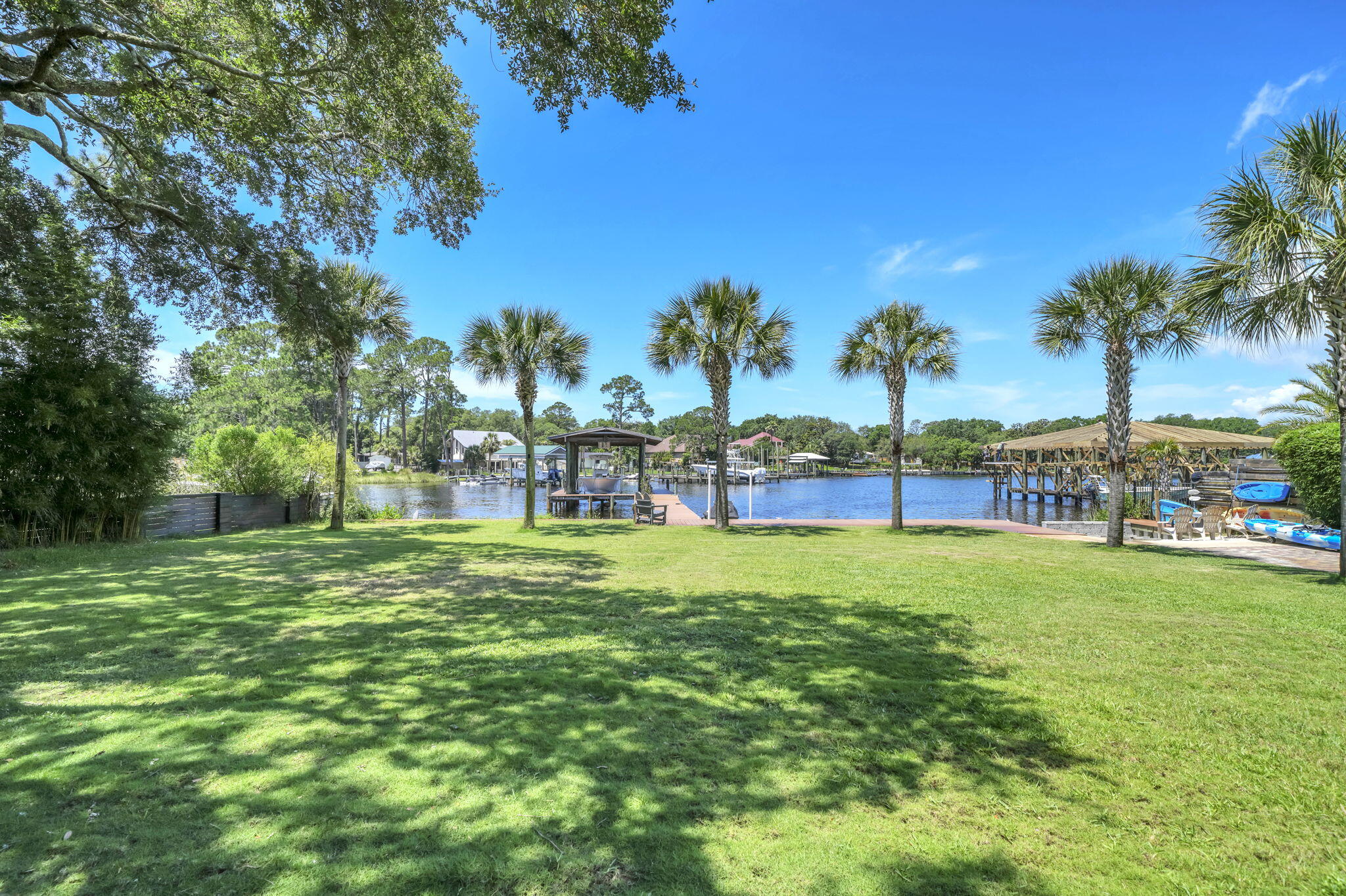 UNDER CONTRACT, TAKING BACKUP OFFERS. Tucked away on beautiful Marler Bayou, one of Destin's most sought-after waterfront locations, this beautifully maintained brick home offers the kind of lifestyle people move to Destin to enjoy. With a detached accessory dwelling unit (ADU) already set up as a studio apartment and a location just minutes from Destin Pass, Crab Island, Choctawhatchee Bay, and the Gulf of America, this property delivers a rare combination of waterfront living, flexibility, and convenience. Spend your days boating, fishing, paddleboarding, or enjoying waterfront dining, then come home to your own private retreat beneath the shade of mature oak and magnolia trees.
Inside, you'll find custom touches throughout that make this home anything but cookie-cutter. The spacious living room features soaring 19-foot ceilings and a stunning custom wood feature wall that immediately becomes the focal point of the home. Granite countertops, a custom wood wet bar, beautiful cypress shelving, and thoughtfully selected finishes create a warm, welcoming space that's equally suited for entertaining or everyday living. The spacious primary suite offers vaulted ceilings, a walk-in closet, and plenty of room to relax after a day on the water.
Step onto the screened porch and take in the peaceful bayou setting, coastal breezes, spectacular sunsets, and even Destin's fireworks displays from the comfort of home. The detached ADU includes a sleeping area, living space, and kitchen,  making it ideal for guests, extended family, a home office, creative studio, or private retreat.
Waterfront homes on Marler Bayou rarely become available. Combining custom features, mature landscaping, a detached ADU, and one of Destin's most desirable waterfront settings, this is a unique opportunity to enjoy the very best of life on the Emerald Coast.