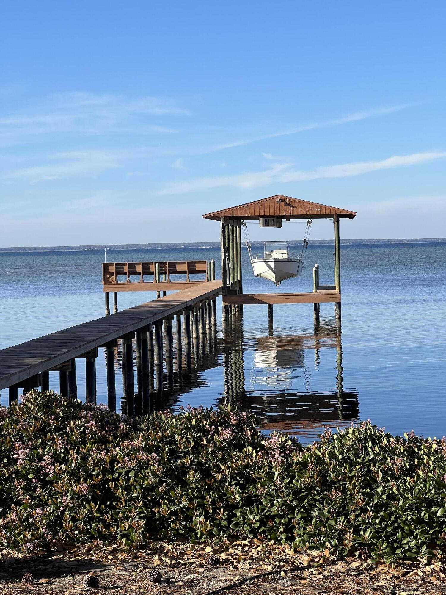 Look East out the kitchen window and see the sunrise; look West from the dock and see spectacular sunsets. Exquisite bayfront residence set beneath majestic Live Oaks, offering privacy, timeless design, and direct water access. This custom-built home showcases refined architectural details including soaring ceilings, tray accents, crown molding, and extensive custom millwork throughout. Expansive windows frame breathtaking water views, filling the home with natural light.

The thoughtfully designed kitchen features Corian and quartzite countertops, solid wood cabinetry, abundant storage, and a center island, 2 sinks and 2 ovens, with a light-filled dining area overlooking the bay. The great room is anchored by a ventless gas fireplace with custom built-ins, creating a warm and inviting gathering space.

A bright all-season room offers additional living space with panoramic views, ideal for year-round enjoyment of the waterfront setting.

The primary suite offers a peaceful retreat with water views and a spacious ensuite bath complete with dual vanities, jetted tub, and separate shower. Bedrooms two and three are connected by a Jack and Jill bathroom, while bedroom four features a semi-private bath, providing ideal accommodations for guests.

Outdoor living is exceptional with a screened-in patio capturing panoramic waterfront views and a beautifully landscaped yard. A private boathouse and dock with covered lift, and a 3-4 foot water depth, enhance the coastal lifestyle, with convenient proximity to the East Pass for quick access to the Gulf.  

Additional features include an oversized 3-car garage, two-zone heating and cooling system, and washer and dryer that convey. Most furnishings are included with the sale, with the exception of select documented items.

A rare opportunity to experience elevated waterfront living with space, functionality, and unmatched natural beauty.