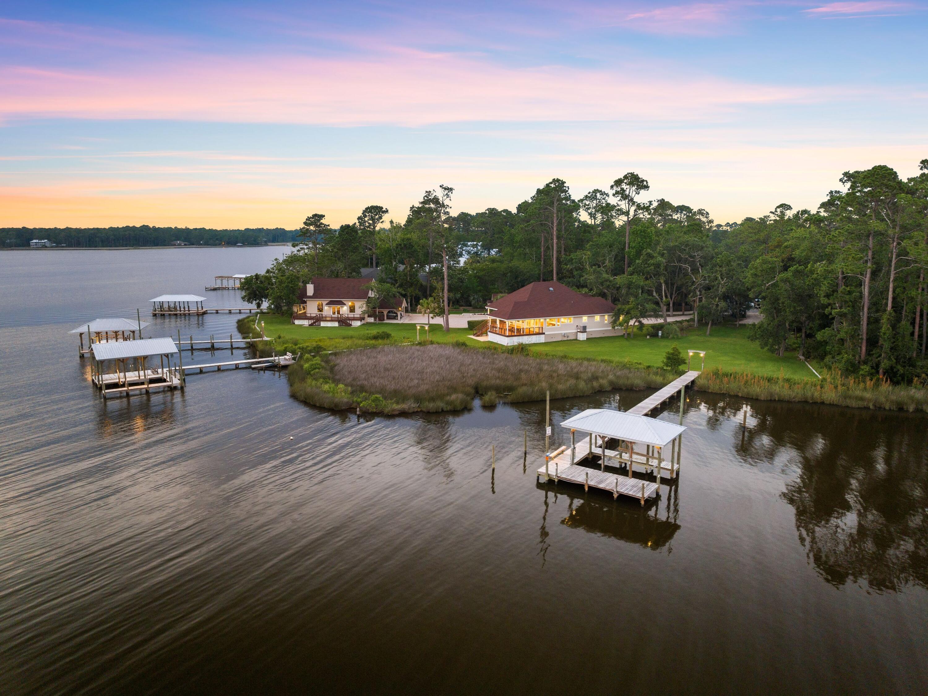 Set on a rare 6.8-acre point along Lagrange Bayou, this offering is unlike anything else on the market in Freeport -- an unmatched combination of 725 feet of waterfront, two single-family homes, a versatile third structure, and three private docks, all positioned to capture the best sunset views on the water.
Perched on the point, this property is oriented to soak in panoramic water views across the bayou and into Choctawhatchee Bay, with front-row seats to some of the most spectacular sunsets in the area. Wildlife is part of everyday life here -- herons wading the shallows, dolphins gliding past the docks, and eagles, osprey, and deer moving through the property's wooded acreage. It's the kind of natural beauty and privacy that simply isn't replicated on parcels of this scale so close to the water. The Main residence offers a single-level, split-plan layout with 3 bedrooms, cathedral ceilings, and a wall of windows framing the water and sunset views. Finishes throughout reflect no expense spared: custom walnut cabinetry, quartzite countertops, hardwood flooring, and hurricane-rated doors and windows. The covered cumaru deck on the south side is the perfect perch for dining or relaxing, with sweeping bayou and bay views and steady breezes off the water year round. 
 A true multi-family or income-generating asset, the second home features 2 bedrooms and 2 bathrooms, a large galley kitchen with hickory cabinets and natural stone countertops, and a two-story layout that feels like its own private retreat. Upstairs offers a bedroom suite with en-suite bath and a library; downstairs opens to panoramic water views and a fireplace for cooler months. Covered parking is also located here.  A third structure currently used as a workshop, creates a bonus or flexible space including a sleeping loft and full bathroom -- ready to become an additional guest suite, private office, or personal getaway. Beyond the seawall, three private docks with open boathouses, boat lifts, and catwalks are already in place. Just bring your boat or jet skis. With this much wooded acreage, waterfront, and privacy rarely -- if ever -- available together in Freeport, the next owner has the rare chance to preserve this sanctuary as-is, add personal structures, or explore development potential on one of the most significant homesites the area has ever seen.