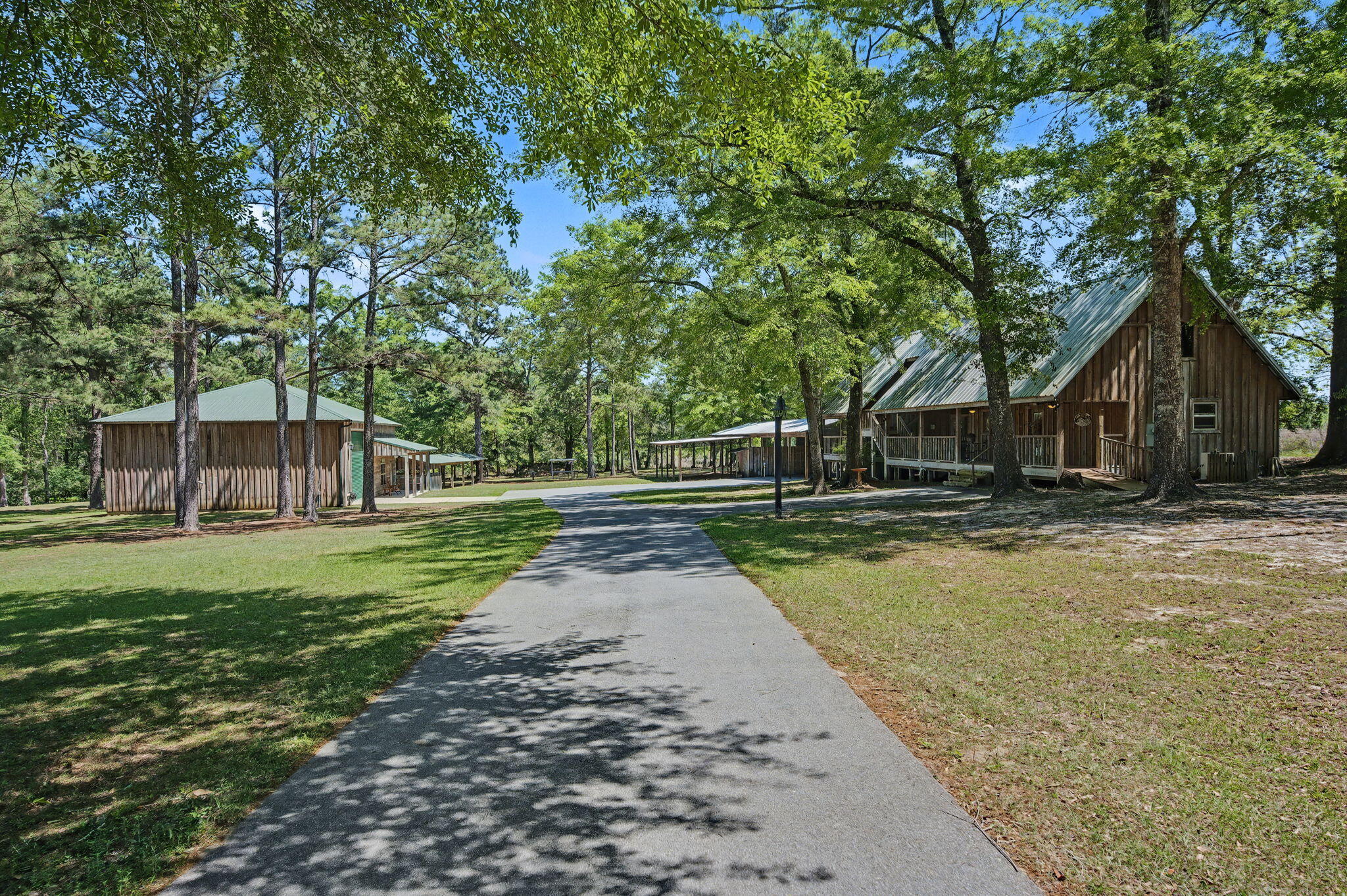 Barndominium living meets rustic cabin charm--two incredible dwellings, one unforgettable property. Perfectly positioned on three gorgeous acres to offer both privacy and connection, this unique setup opens the door to multi-generational living, guest accommodations, income potential, or your own private retreat experience. The barndominium showcases impressive 16-foot ceilings, 2x6 construction, and energy-efficient spray foam insulation. Warm cypress walls and stained concrete flooring create a striking yet comfortable aesthetic, while the kitchen features granite countertops, stainless appliances, and a gas stove--perfect for everyday living or entertaining. A heavy-duty sliding barn door clad in galvanized ribbed metal adds character as it separates the living space from the expansive  20x40 attached garage, complete with a LiftMaster automatic roll-up door and ample space for an RV or up to four vehicles. Step outside to a 30' covered porch featuring a wooden swing and classic Adirondack seating--an ideal spot to relax and take in the peaceful surroundings. The rustic cabin guest house feels like a true mountain escape right here in Northwest Florida, with cypress walls, flooring, ceilings, and spray foam insulation throughout. Designed with intention, the bedrooms are positioned as private retreats, each accessed by covered deck walkways--offering a sense of separation perfect for guests or multi-generational living. The primary suite delivers a one-of-a-kind, open-concept spa experience with a clawfoot soaking tub, walk-in shower, and custom vanity, creating a relaxing lodge-style atmosphere. Outdoor living shines with a spacious deck featuring a two-person hot tub and a rustic rinse station with hot and cold water--perfect for unwinding after a day outdoors. Abundant storage throughout adds to the functionality of this thoughtfully designed space. Beyond the homes, the property continues to impress with a decorative gated entrance featuring WiFi remote access, a winding asphalt driveway, and your very own private shooting range just steps away. Additional features include an adorable chicken coop, a 24' x 100' pole barn with covered four-stall parking and an 18' x 48' lean-to, plus a 13' x 60' pole barn ideal for gatherings, cookouts, or entertaining. Located just minutes from Blackwater River State Forest, you'll have easy access to canoeing, fishing, hiking, camping, hunting, swimming, and horseback riding--bringing the very best of outdoor recreation right to your doorstep. This is more than a property--it's a lifestyle. Whether you envision a hunting retreat, private getaway, Airbnb opportunity, or even an event venue, the possibilities here are endless.