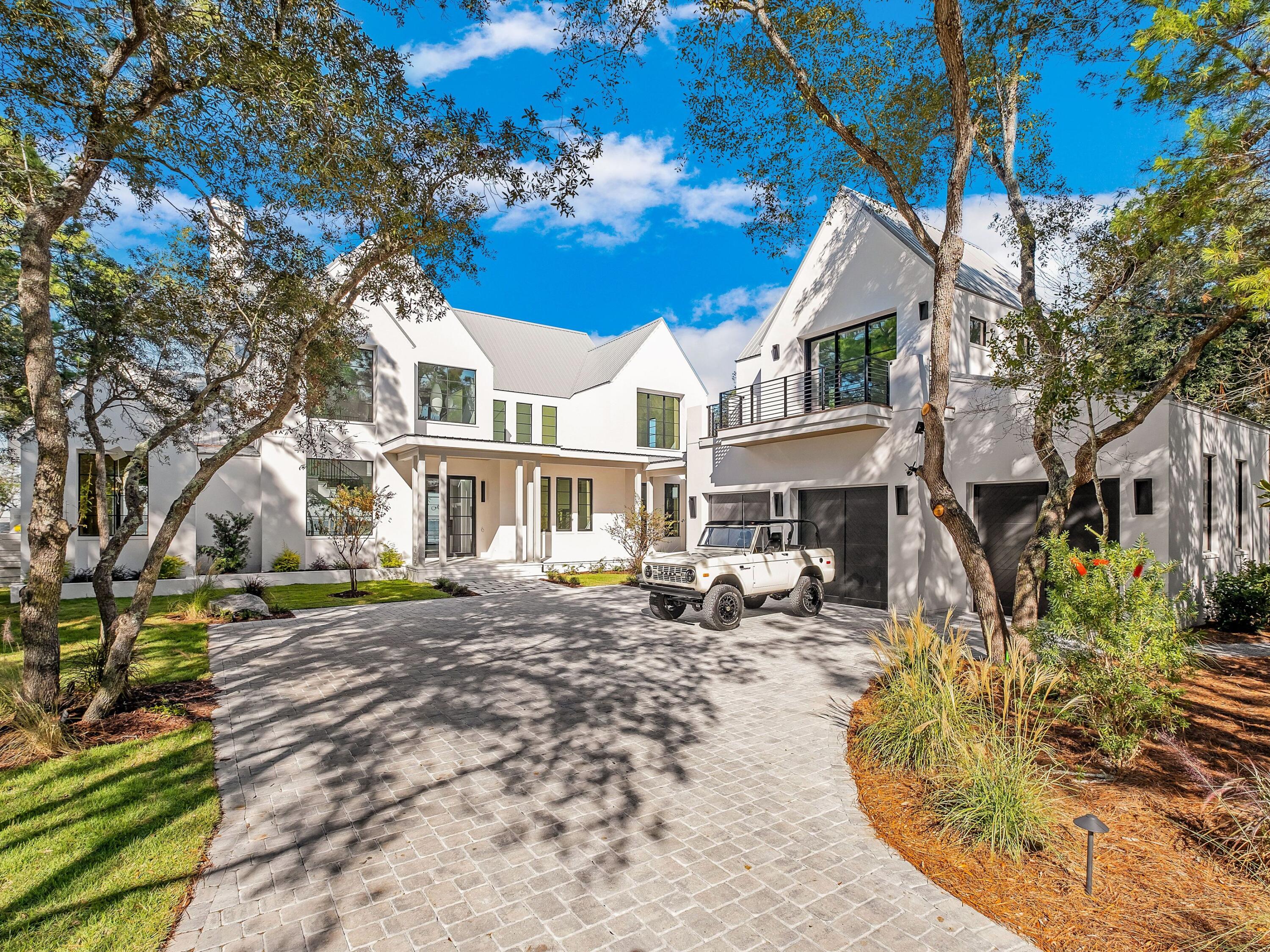 Expertly designed and built by Coastal Elements with architecture by Greg Jazayeri, 431 Pisces Drive is a newly completed bayfront estate where contemporary coastal design meets elevated craftsmanship. Set on over half an acre with 100+ feet of private water frontage, the home sits along a quiet cul-de-sac of just fourteen bayfront residences, offering private deep-water access, protected serenity, and effortless proximity to 30A, Destin, and Panama City Beach. From your private dock, mornings begin on a paddle board and weekends turn into spontaneous trips to the Gulf for offshore fishing, exploring sandbars, or boating to your favorite local restaurants at sunset.
From its earliest conception, the home was designed to live in dialogue with the land. Mature live oaks were intentionally preserved, framing the residence with a sense of permanence and authenticity. Smooth white stucco, streamlined rooflines, Brazilian hardwood accents, and large hand-placed concrete pavers create a clean, modern silhouette softened by the natural canopy around it. The result is architecture that feels quietly timeless, rooted, and distinctly refined.

Inside, the home unfolds with Venetian plaster walls, vaulted beam ceilings, custom white oak cabinetry, and hand-selected marble tile and countertops. The open living and dining spaces are anchored by panoramic bay views, connecting seamlessly to the covered veranda and pool terrace. The kitchen features cabinet-finish premium appliances, a sculptural range wall, a refined butler's pantry, coffee bar, and generous storage designed for everyday livability and elevated hosting.

The 6-bedroom layout includes all en-suite accommodations and 2 additional half baths, including one conveniently positioned for poolside use. The primary suite enjoys a private wing on the first level with vaulted white oak ceilings, dual custom closets, and a spa-caliber bath of Italian marble with a grand walk-in shower. A wall of glass completes the room that captures sweeping bay views, allowing you to wake to glass-smooth water and step directly onto the veranda for quiet sunrise moments and a seamless connection to the outdoors.

Upstairs, a secondary living room opens to a private balcony overlooking the water, accompanied by three guest suites. A detached carriage house and three-car garage allow for flexible living, privacy for guests, or dedicated space for lifestyle gear.

Outdoors, the estate is designed for both quiet reflection and memorable gatherings: a summer kitchen, bayfront fire feature, private dock ready to host a substantial vessel, a resort-style pool, and a separate fire pit lounge beneath the preserved live oaks. The curved brick paver driveway completes the sense of arrival.

Here, the bay is a lifestyle, sunrise coffee on the veranda, effortless boating in the afternoons, evenings by the water with firelight and salt air.