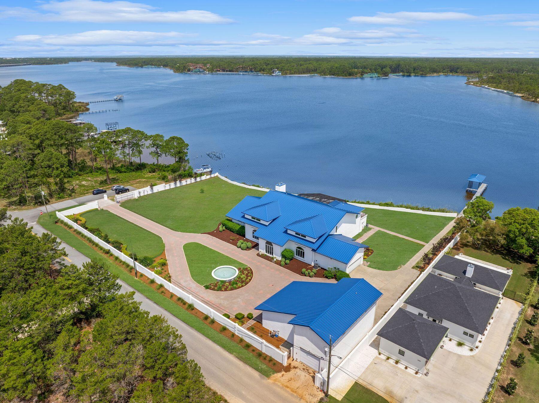 Offering 330 feet of waterfront on Florida's largest coastal dune lake, this luxury residence is sure to appeal to golfers, boaters and fishing enthusiasts. Located across the lake from Sharks Tooth Golf Club this residence is secured behind a walled perimeter and a privacy gate. This outstanding home sits on 2.12 acres of prime lakefront and includes a lengthy private dock and boathouse. Venture inside, and this recently remodeled custom-built home will take your breath away with its soaring 24-ft. vaulted ceilings, which dwarf the windows and doors in the great room. A second floor mezzanine overlooks the grand piano in the vast sitting room, which has an equally lofty contemporary fireplace feature.