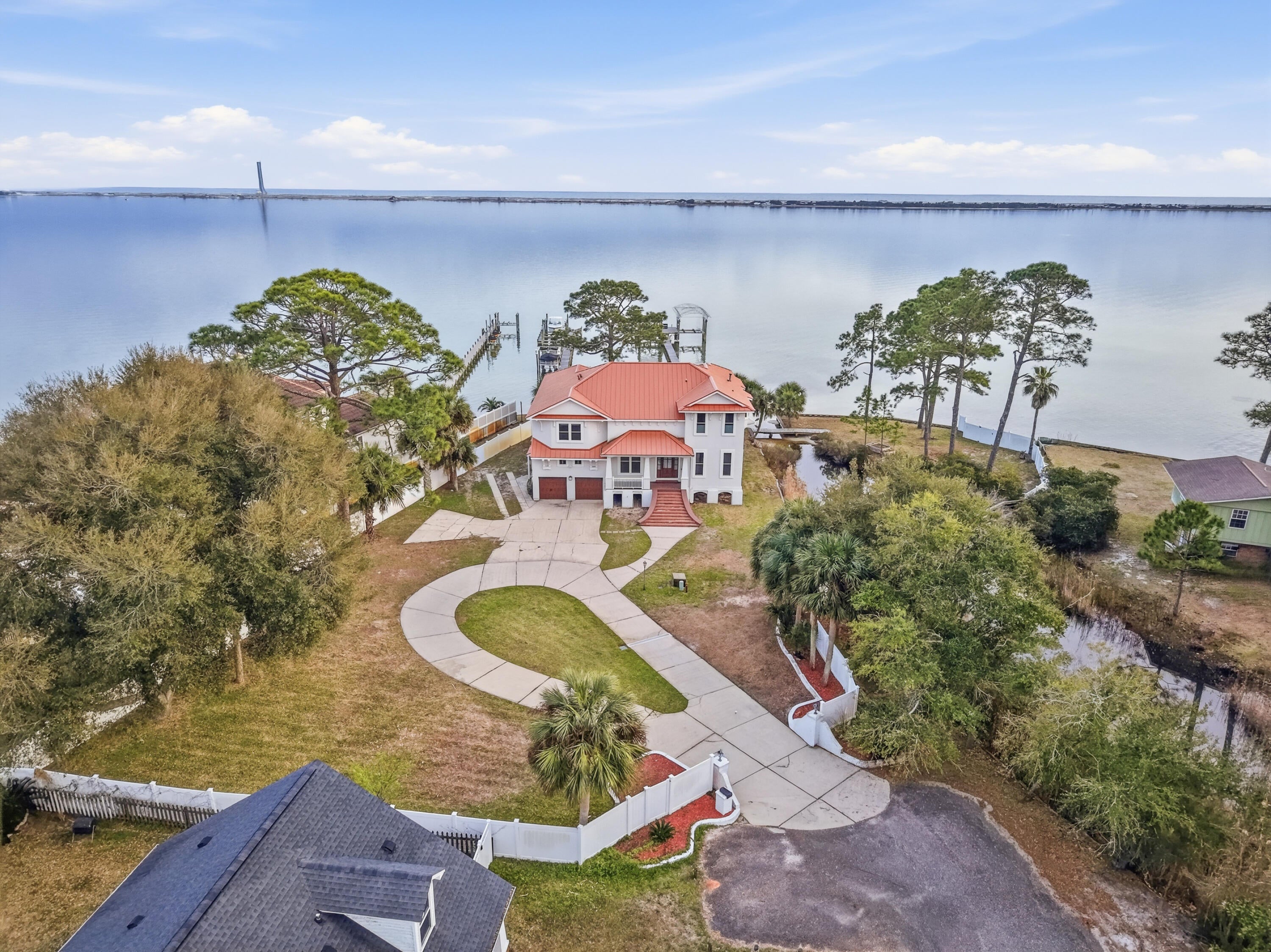 On the Intracoastal waters of Santa Rosa Sound, this elevated coastal contemporary residence offers exceptional privacy and sweeping waterfront views. Positioned at the end of a private street in Mary Esther, the home is bordered by the sound and framed by stately brick column entry walls.  Current waterfront pricing in Navarre and Mary Esther range from $700-$474 a square foot.  This home is priced below $333 a square foot due to a few dated items.  The tile floors on the first floor are in exceptional shape but have a dated appearance.  Also, the kitchen and bathrooms are slightly dated.  Estimates around $200,000 for all of the updates will easily bring this home into the $500+ a square foot range.  Instantly bringing the value of the home into the 2M dollar range.  Owner does not live in the area and does not want to manage the updates.  This home will have instant equity with the right buyer and vision..

All of the stucco has been replaced with an entirely new exterior.  All 53 windows were replaced during the stucco with flanged hurricane windows.  New all aluminum roof.

Inside, five bedrooms, two bonus rooms, three full baths, and one half bath are thoughtfully arranged to maximize natural light and panoramic water views. Nearly every room overlooks the sound, allowing the waterfront to shape daily living. Dock includes 2 boat lifts.  The primary boatlift supports a 18,000 lb boat.