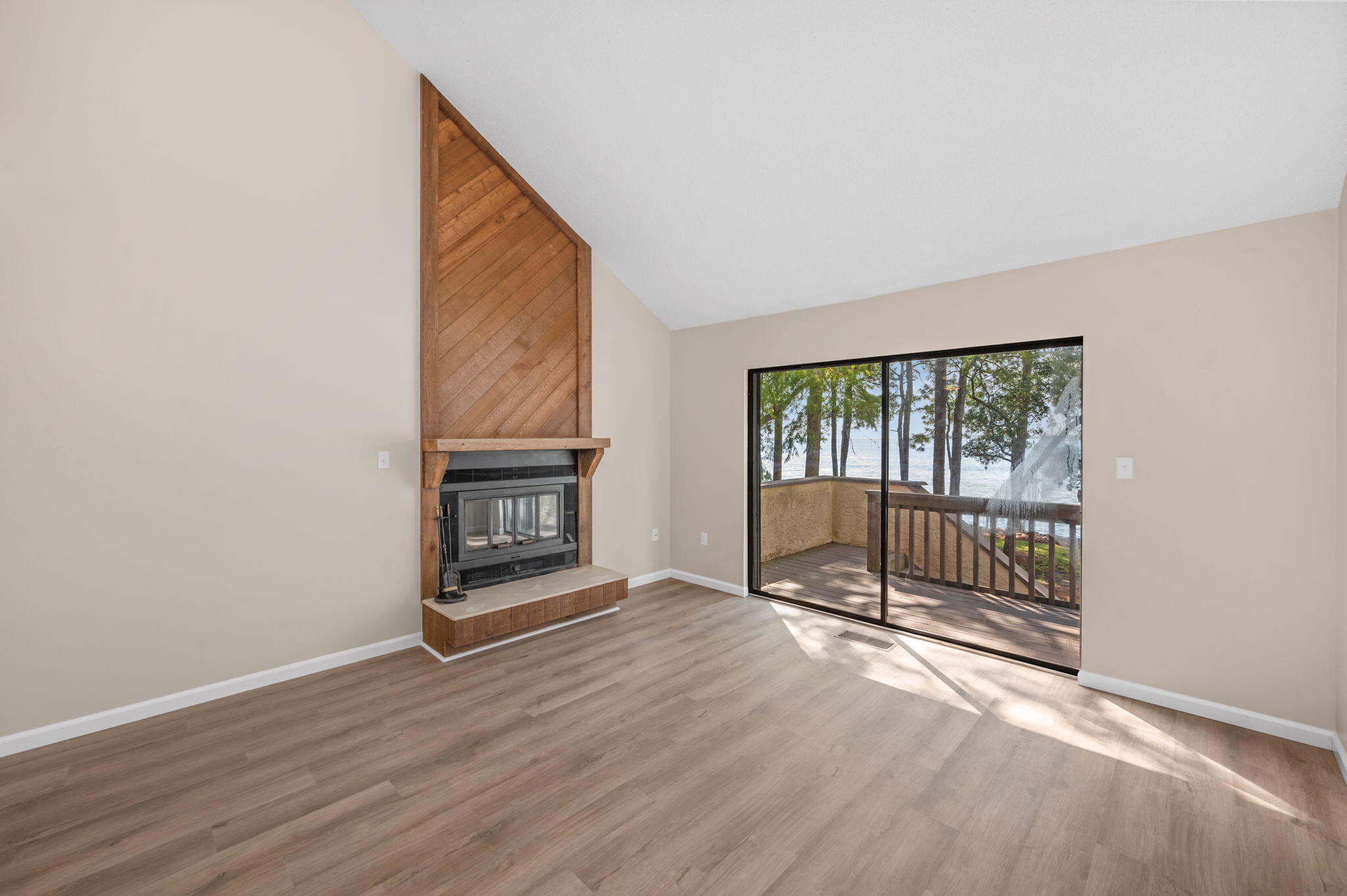 Enjoy stunning water views from all three levels of this beautifully updated 2-bedroom, 3-bath home. Featuring fresh paint, crisp trim, and luxury vinyl plank flooring throughout, this residence combines comfort and coastal style.
The renovated kitchen offers stainless steel appliances and a bright, open feel perfect for entertaining. The spacious living area includes a wood-burning fireplace, soaring multi-level vaulted ceilings, and access to a screened-in patio overlooking the water. The primary suite boasts a vaulted ceiling, walk-in closet, dual sinks with an extra-long vanity, and a separate water closet with a walk-in shower enclosed in glass. A second bedroom and full bath with a shower-tub combo provide plenty of space for guests, while a full bath on the main level adds