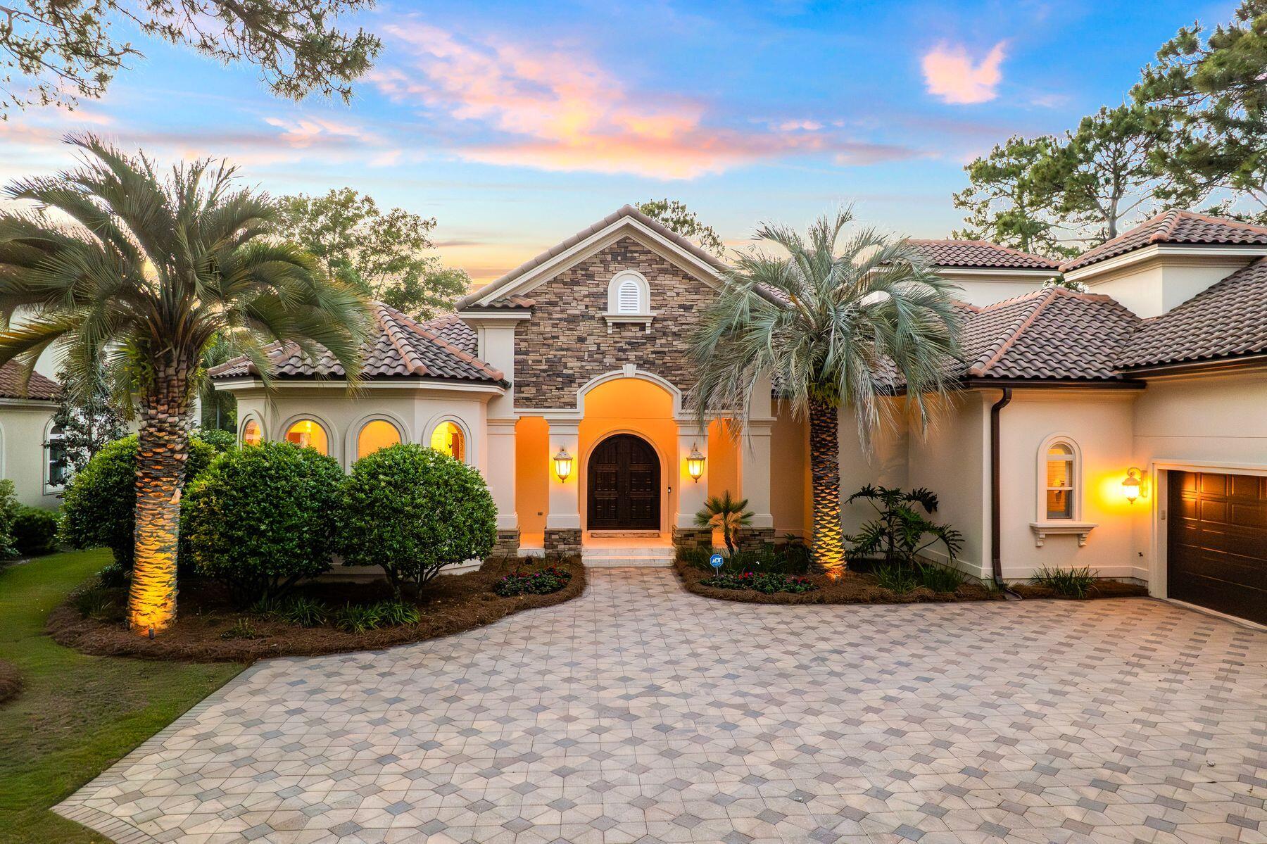 Beyond a quiet stretch of the Raven #9 manicured fairway and behind the Burnt Pine gates in the prestigious Arrowhead neighborhood, this residence unfolds with a sense of ease and intention -- where architecture, light and landscape come together in a way that feels both elevated and entirely livable. Framed by a paver drive, tropical landscaping and a stately arched entry, the home makes an immediate impression, then continues to reveal layers of thoughtful design and refined detail.

Inside, the main living area feels both grand and inviting, anchored by a gas fireplace, refined millwork and expansive windows that draw in natural light while connecting seamlessly to the outdoor living spaces. The chef's kitchen is equal parts striking and functional, appointed with high-end appliances, custom cabinetry, intricate stonework and a large center island that naturally becomes the heart of the home.

The layout is intentionally designed for convenience and flexibility, with the primary suite, a guest suite and a dedicated office all located on the first floor. Each of the four bedrooms features its own ensuite bath, complemented by a total of five full baths throughout the home. The primary suite serves as a private retreat, complete with a tray ceiling, abundant natural light and a spa-inspired bath with soaking tub and walk-in shower.
Upstairs, additional living space creates options for relaxed evenings or entertaining, while the bonus area above the garage offers remarkable adaptability. Currently utilized as a fitness space, it can easily transition into a game room, bunk room or private guest retreat.

Outdoor living is equally compelling, centered around a screened lanai with a gas fireplace and a distinctive saltwater pool and spa. Overlooking the Burnt Pine golf course, the setting feels both private and serene, with ample space for lounging and dining throughout the seasons. A whole-home generator adds an additional layer of comfort and peace of mind.

As part of Sandestin Golf and Beach Resort, residents enjoy access to an exceptional collection of amenities, including championship golf at Raven, The Links and Baytowne courses, the Sandestin Beach Club, Baytowne Marina, tennis and pickleball facilities, scenic walking and biking paths and the natural beauty of Jolee Island. Additional conveniences include multiple community pools, The Village of Baytowne Wharf, Grand Boulevard and the Market Shops. Optional membership to Burnt Pine Country Club further enhances the experience with exclusive golf, dining and social opportunities.