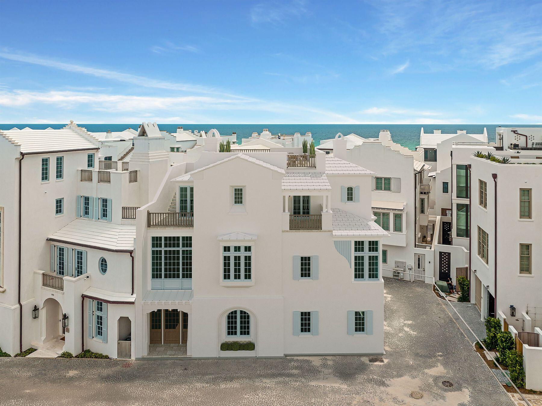 AC 27 sits south of Sea Garden Street, on the Gulf side of town where Alys Beach is at its quietest. The homesite fronts Verdmont Way, a short lane with no through traffic that leaves Sea Garden Street and ends at the green ellipse of Béla Gray, with the Turtle Bale Pedestrian Path to the beach at the foot of Sea Castle Alley. Third row from the sand and tucked away from the activity of the town center, it remains an easy walk to the Beach Club, Caliza, and the restaurants and shops.
The homesite conveys with approved plans by Tim Adams, Veranda's 2024 Southeast Architect of the Year, whose firm T.S. Adams Studio has a long record of award-winning work in Alys Beach. The design places four bedrooms and a bunk nook across three levels, with 3,373 square feet of conditioned space and 4,812 square feet under roof. A true two-car garage, uncommon on the south side, enters discreetly from Old Cellar Lane and leaves the Verdmont Way facade to the limestone-columned entry porch, the arched fountain niche, and the timber-
framed bays above.
Two guest suites, a bunk nook, and a sandroom off a private courtyard anchor the ground level. The main floor is a single generous room in the Alys Beach tradition: a 34-foot great room and kitchen under twelve-foot ceilings, framed in stained cypress beams and finished in plaster, with a limestone fireplace at one end and a working pantry, bar, and powder room tucked behind the kitchen. Arched openings lead to a loggia with its own fireplace, and beyond it a second-story garden terrace with the pool, integrated spa, and planted borders, screened from the street. The top floor belongs to the primary suite, with a window seat, two walk-in closets, and a bath with a freestanding tub and walk-in shower. A third en-suite bedroom, a laundry, and a vaulted balcony complete the level. An elevator serves all three floors, and a stair of oak treads and iron rail climbs through a plaster stair hall beneath cypress beams. Above it all sits a 617-square-foot roof terrace with a third fireplace and a wood balustrade. Ownership includes the town's private amenities: 1,500 feet of Gulf shoreline with beach setups and food and beverage service, the homeowner-only Beach Club, Caliza Pool and Restaurant, the 15,000-square-foot ZUMA Wellness Center and Racquet Sports Facility, and The Silva, with its restaurant and pool at the edge of a 20-acre nature preserve.
Approved plans convey with the homesite, and construction must commence by June 2027. A Buyer can break ground in months rather than years.