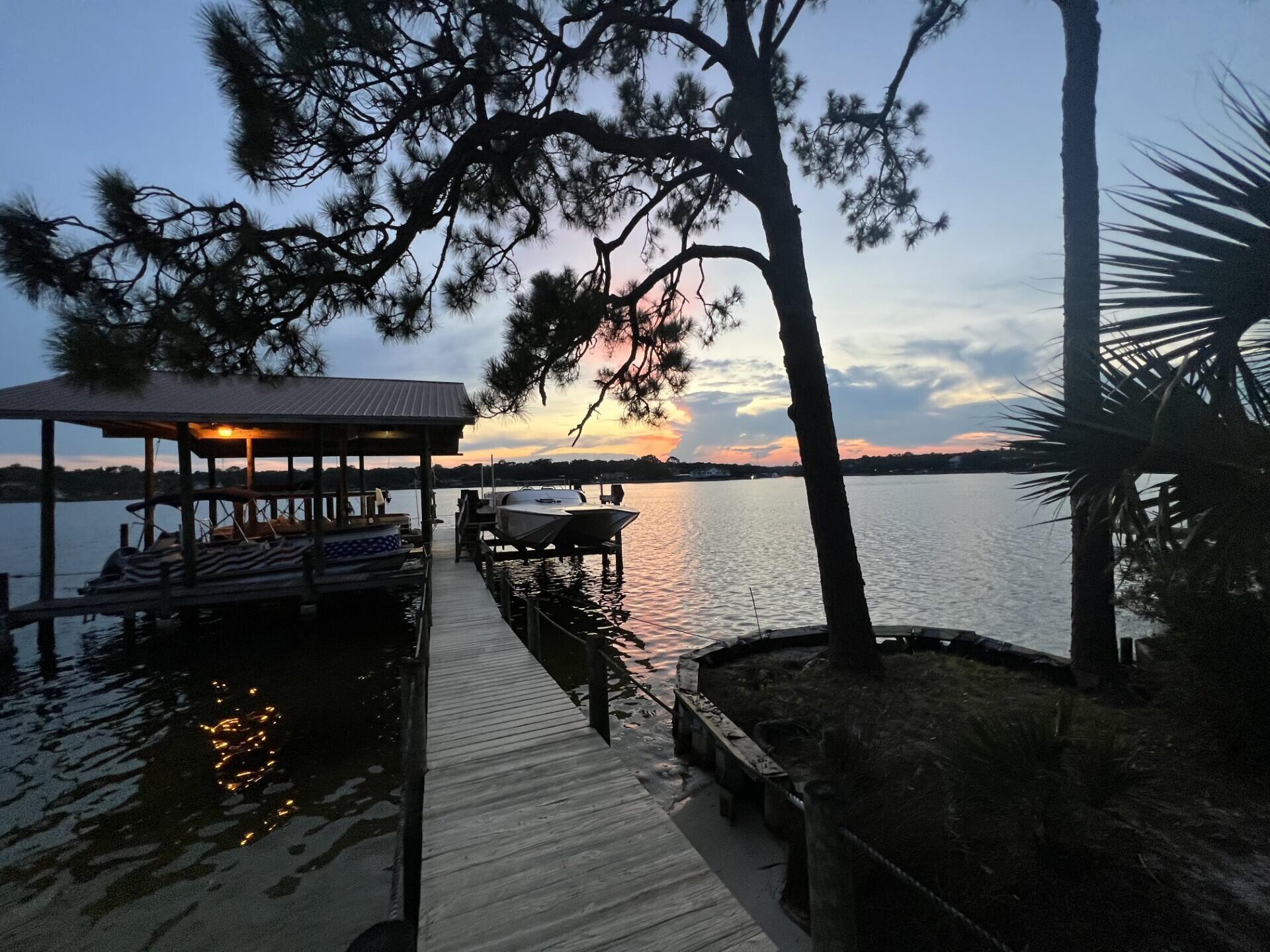 WATERFRONT HOME with BREATHTAKING SUNSETS!!!! Come view this Beautiful 5 bedroom, 4-full, 2-1/2 baths home with a personal office or gym room.  Don't forget the detached 3 car garage with 1 bedroom and half bath above. Perfect for a college student or a media room. This home was made for entertaining and the avid boater.  Enjoy 3 boats lifts. The 3rd lift was added in 2024 (20,0000) lb. lift. In July. 2026 the 4x37 access to pier and 48x36 covered boathouse with 2 slips and interior catwalks, upper deck and covered deck with boathouse were sealed with 10-year Valspar stain & sealer.   In 2023, all new ceiling fans, new light fixtures, toilets, sinks, countertops and vanities in bathrooms, bathroom mirrors, remodeled shower in master, ceilings scraped throughout and painted, shiplap added in master bedroom, master bathroom, other bathrooms, ''new hardware and faucet in the kitchen, master shower, guest shower, doors, sinks. Other upgrades in 2023,  the home received all new Interior and Exterior paint, new upper cabinets in 2 of the bathrooms, tile flooring in the lower hallway. 2 baths and laundry room.  A metal roof was installed on the home in 2012. In 2016 the kitchen was remodeled and more updates added in 2023.  In 2016 new roof was installed on the detached garage, 2017 electrical wiring and gas were installed with a whole house generator. Updates and controllers were added to the generator in 2022. In 2019 11 windows in back of the home were replaced with high impac glass.  The kitchen and den open up through French doors to a 23x40 covered back porch.  Whether you're having a cup of coffee or ending the day with a glass of wine, this is a perfect setting! There's an extended gas grill in place for all your cookouts and the area is large enough for several sets of patio furniture.  If you decide to take the party to the docks, you'll enjoy the beach area for everyone to play, float and put the paddle boards or kayaks in the water. Enjoy two separate decks with some covered area by the boat house for those who would like to be on the water, but need some shade. Don't worry about storage for all the floats.  The boat house is big enough to store your fishing gear, crab traps, floats and enjoy a quick shower before coming back up to the house.  The outside shower is located up on the deck next to the boathouse.  Everything is covered! Don't forget about all the dolphins that you'll get to see along with all the other marine life. This is a Very Special property in a very sought out area in Poquito Bayou. Minutes away from Eglin, and Special forces. It sits further back in the bayou yet minutes away from Crab Island, shopping and restaurants by boat. Upkeep of the yard is made easy with the updated sprinkler system in 2023. Call today for a viewing!