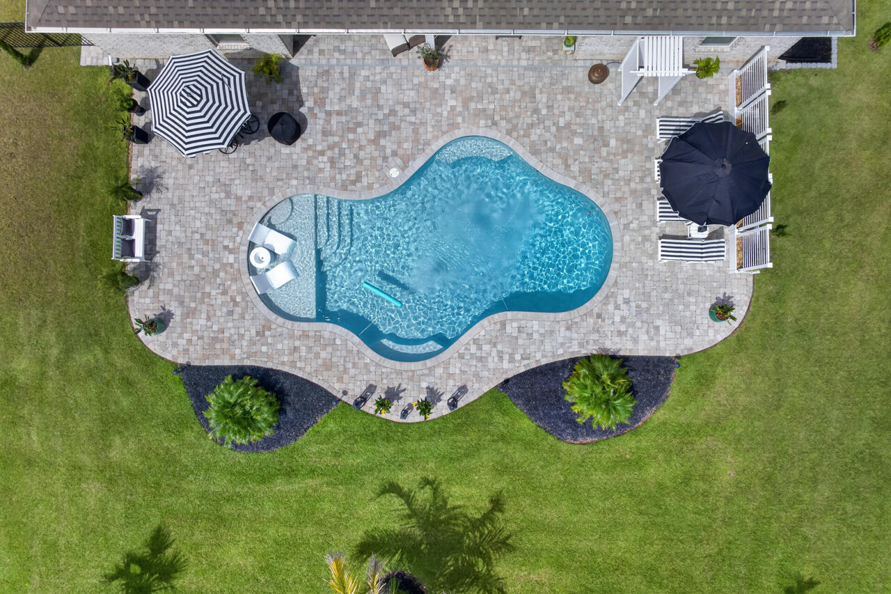 THIS is what elevated Florida living looks like. Set on an oversized .60-acre homesite in gated Windswept Estates, this impressive 4-bedroom, 3-bath, 3,322-square-foot all-brick residence has been transformed far beyond builder standard into a home that feels polished, private and remarkably complete.

The backyard is pure resort-style living. A gorgeous in-ground pool with cascading water features takes center stage, surrounded by an expansive paver patio designed for entertaining, dining and unwinding in the Florida sunshine. Lush landscaping, new palm trees, fresh sod, a fully fenced yard and professional landscape uplighting create a spectacular setting that becomes even more beautiful after sunset.
Inside, a thoughtfully designed split-bedroom floor plan offers exceptional space and flexibility while maintaining a sense of privacy. The grand primary suite is a retreat all its own, complemented by an enormous ensuite featuring an impressive double vanity with abundant counter space, beautifully upgraded finishes, rain-head shower and a generous walk-in close.

Throughout the home, plantation shutters, quartz countertops, upgraded lighting, custom barn doors and a coffered dining room ceiling add sophisticated character. The gourmet kitchen is equally impressive with a new induction range, convection microwave, upgraded appliances, custom backsplash, under-cabinet lighting, upgraded hardware and beautifully detailed island--ready for everything from morning coffee to evenings spent entertaining.

With approximately $50,000 in builder upgrades PLUS extensive post-closing improvements, this is more than a beautiful pool home--it is an opportunity to step directly into the Florida lifestyle without waiting to build, landscape or upgrade.

And the lifestyle extends well beyond your front door. Windswept Estates is known for spacious homesites, low HOA dues and an impressive collection of amenities, including a clubhouse, community pool, playground, tennis and pickleball courts, pavilion, food trucks and neighborhood holiday gatherings--all surrounded by the natural beauty of the 18-hole championship Windswept Dunes Golf Course.

This isn't simply a beautiful home with a pool. It's morning coffee overlooking your private backyard retreat, afternoons by the pool , evenings entertaining under the lights and the space to enjoy it all. Come home, turn on the pool fountains and discover just how good Florida living can be.