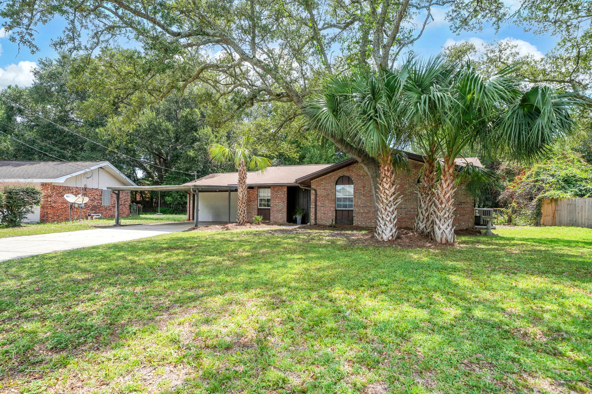 Need a spacious back yard for pets, gardens, or hosting guest for outdoor gatherings? This .38 acre lot is perfect for weekend barbecues and throwing a football! This home has 3 bedrooms, 2 baths, and 1316 sq ft. The location of this home makes it very desirable with the military bases, shopping, and the beaches only minutes away! The two car garage plus the carport is perfect for covering vehicles and trailers! A newer roof (2019) and HVAC (2016) brings financial peace of mind. The home owner updated the flooring to Luxury Vinyl Plank (2026) and Carpet (2026).  Since the interior is newly painted (2026) moving in will be no problem! Other updates recently completed include: new interior lighting and new faucets and fixtures. The galley kitchen is spacious and has a slide in stove and oven, refrigerator and rangehood. The living room features a fireplace with a mantel (fireplace door glass on order), vaulted ceilings, and a new ceiling fan. There are three nice sized bedrooms. The primary bedroom has a large picturesque window overlooking the back yard, a walk in closet with shelving, and an ensuite bathroom. The dining room features a new chandelier and the eat kitchen also has new lighting. In true Florida style, this home has a large Florida room! This space provides additional room to entertain guests, have a second TV or media room, a workout room or just a place to relax. There is also an underroof storage room attached to the garage that is perfect for storing tools and outdoor equipment. Gutters, a storm door, a lawn pump, and a small shed are other exterior home features.  Buyer to verify all dimensions and information.