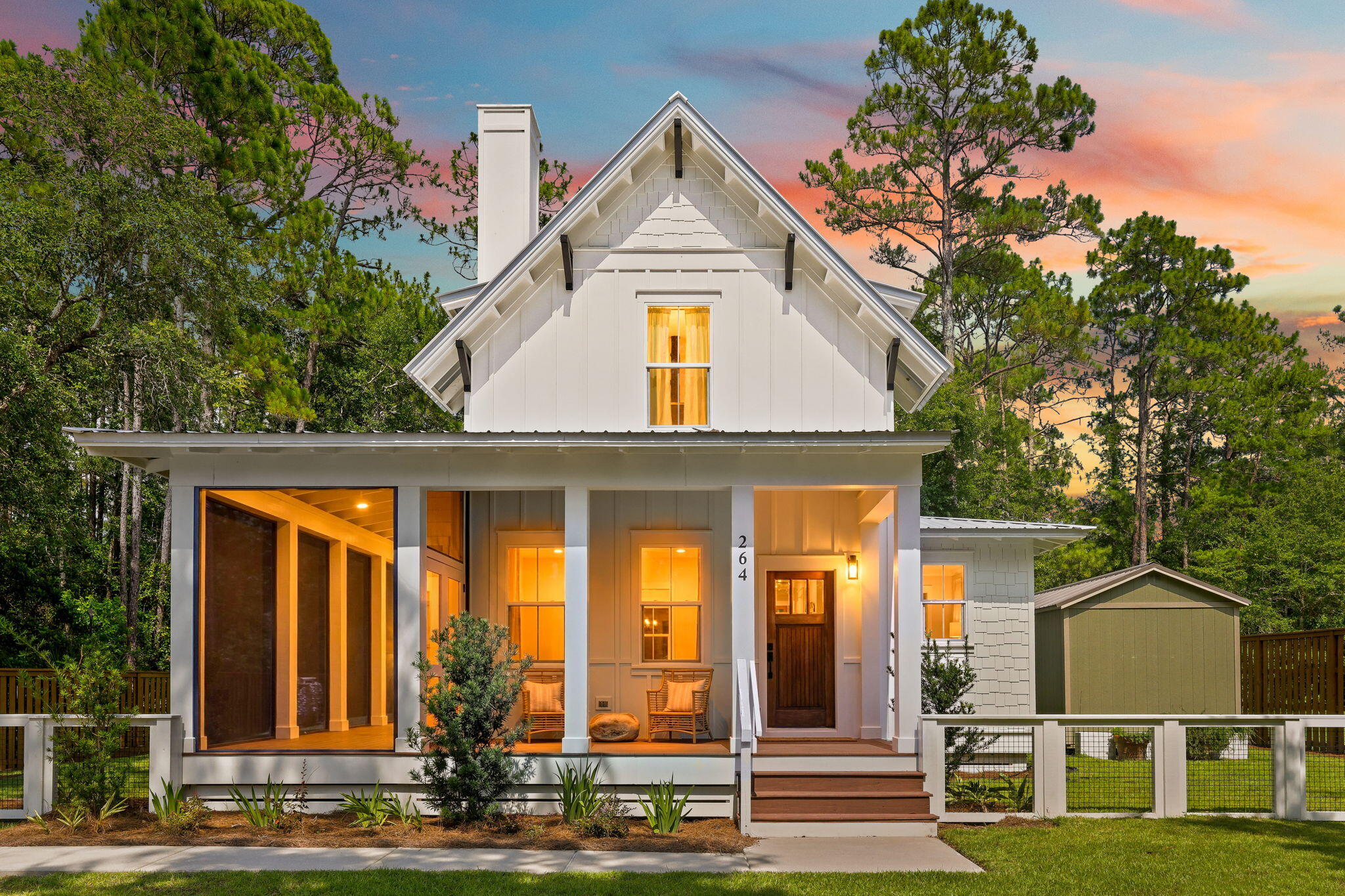 *CURRENTLY UNDER CONTRACT, SELLER WILL CONSIDER BACKUP OFFERS* Tucked beneath towering pines just steps from a quiet bayou, this home has the kind of curb appeal that stops people mid-walk. The wraparound covered porch and screened-in sitting area set the tone the moment you arrive, framed by a classic white wood-and-wire fence and a dusk sky that turns the whole scene into a postcard.

Through the craftsman-style wood door and the open-concept main floor does all the talking: wide-plank hickory floors flow from the entry through a living room with a shiplap-accented fireplace, into a dining nook, and straight into a kitchen built for someone who actually cooks. Think white shaker cabinets, quartz counters, a custom vent hood, a tile backsplash with real texture, and stainless appliances throughout- plus a center island with room to gather.

The main-floor primary suite is a genuine retreat, with a spa-style bathroom, a walk-in closet, its own private covered deck, and a nearby laundry room that keeps everyday life easy. Upstairs, two additional bedrooms -- each with dual closets -- share a well-appointed bath, giving guests or family their own private wing.

Outside is where this property really sets itself apart. A 24-foot screened porch off the living room is practically a second living room, complete with a hanging rattan chair swing, and it opens onto a fenced backyard shaded by mature oaks and pines. The aerial view says it all: this lot backs up to a quiet, tree-lined