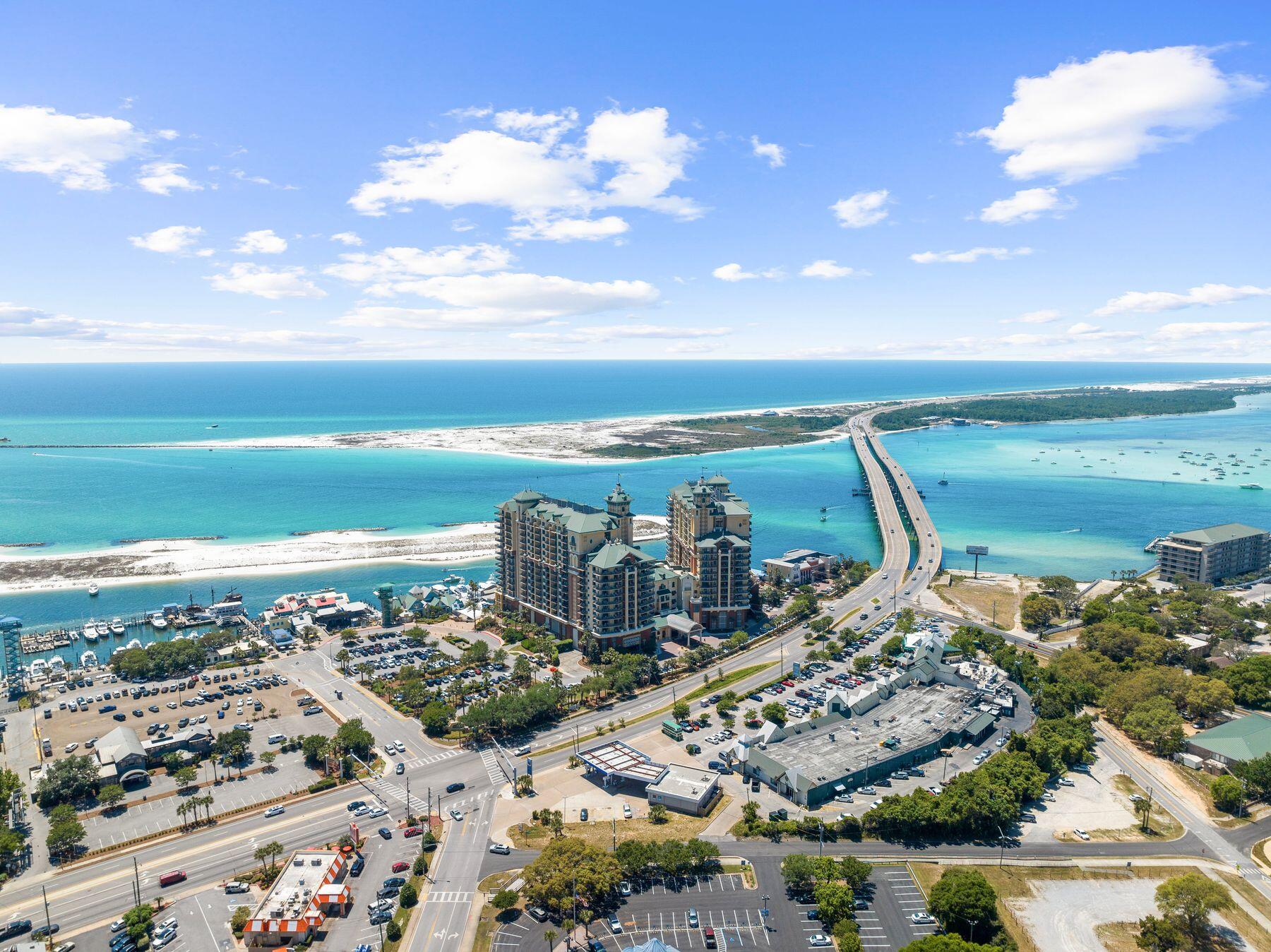 Positioned high above the Destin Harbor, this beautifully renovated residence at Emerald Grande offers an exceptional combination of space, comfort and panoramic coastal scenery. One of the largest three-bedroom floor plans in the building, the residence is designed for effortless entertaining with an expansive open-concept layout, generous living and dining areas and walls of glass that frame remarkable views stretching across Destin Harbor, Choctawhatchee Bay, Crab Island and the Gulf of Mexico. At the heart of the home, the spacious kitchen features granite countertops, stainless steel appliances, a breakfast bar and abundant cabinetry, allowing conversations to flow seamlessly from the kitchen to the dining and living spaces. Nine-foot ceilings, crown molding and thoughtfully selected finishes create an inviting atmosphere throughout, while Italian porcelain tile adds a refined touch to each bathroom. The well-designed floor plan comfortably accommodates family and guests with two private primary suites, each offering tranquil water views and direct balcony access. An additional guest bedroom provides flexible sleeping arrangements, making the residence equally suited for full-time living, a vacation retreat or an investment opportunity. One of the home's most impressive features is the expansive wraparound balcony spanning more than 400 square feet. Whether enjoying sunrise over the bay, watching boats cruise through the harbor or taking in spectacular sunsets over the  gulf, this outdoor living space offers an ever-changing backdrop for morning coffee, evening cocktails or simply relaxing in the coastal breeze. Emerald Grande offers an outstanding collection of resort-style amenities designed to elevate every stay. Residents and guests enjoy a secure parking garage, indoor and outdoor pools, a waterfront hot tub, full-service spa, fitness center, business center, on-site restaurant and bar, plus boutique shopping. A private boat shuttle provides convenient access to the resort's sugar-white sands and its private beach, widely recognized as one of the area's premier snorkeling destinations. Just outside your door, HarborWalk Village places Destin's vibrant waterfront lifestyle within easy reach. Charter a world-class fishing excursion, board a dolphin cruise, rent a pontoon boat or jet ski, browse waterfront shops or enjoy an outstanding selection of restaurants and live entertainment. Weekly fireworks over the harbor create an unforgettable finale to warm summer evenings, making every visit feel like a celebration.