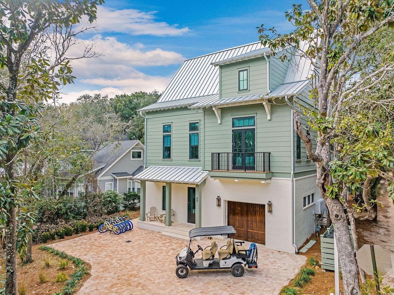 Defined by a clean coastal exterior of white brick, Hardie plank siding, and a metal roof, 69 Live Oak Street presents a timeless architectural profile across four thoughtfully designed levels, the result of a collaboration between architects Leslie Schwartz and Rob Bounds of 30A North Design and builder Timothy O'Hara of Coastal Custom Builders. Seamlessly set among the old growth oaks of Old Seagrove, and ideally positioned just 200 yards from the Live Oak Street beach access, the home offers convenient proximity to the Gulf while maintaining a sense of privacy. A dedicated game room anchors the ground floor, where soaring 12-foot ceilings frame a relaxed gathering space with ample seating, shuffleboard, and pinball. Just beyond, the outdoor living area extends the experience with a private pool, spa, and fully equipped summer kitchen--designed for seamless indoor-outdoor entertaining. Two king guest suites offer privacy and comfort, setting the tone for the home's ability to comfortably accommodate guests from the moment you enter. A half bath, full laundry room with dual washers and dryers, owner's storage, mudroom, and garage complete the level, all connected by elevator service to the upper floors.   
The main living level unfolds with an open layout designed for hosting at scale. A spacious den and secondary sitting area flow into a dining space that comfortably accommodates large gatherings, all centered around a chef's kitchen featuring a 6-by-14-foot quartz island, 48" dual fuel Wolf range, and integrated Sub-Zero refrigeration. A secondary prep area provides additional workspace and storage, supporting effortless entertaining. This level also includes a private king suite and a bunk room with custom queen-over-queen accommodations, further expanding the home's flexible sleeping capacity.

Upstairs, the primary suite offers a quiet retreat, complete with a spa-like bath featuring dual vanities, a soaking tub, and a separate shower, along with direct access to a spacious balcony overlooking the backyard. Additional king guest suites and dual bunk configurations create a layout designed to comfortably host large groups while maintaining a sense of privacy throughout.
The fourth level is dedicated entirely to an open-air rooftop deck, where treetop views of Old Seagrove and expansive skies create a setting equally suited for morning coffee or evening gatherings.
Designed with both lifestyle and performance in mind, the home accommodates up to 28 guests and presents an opportunity meaningful annual rental income.