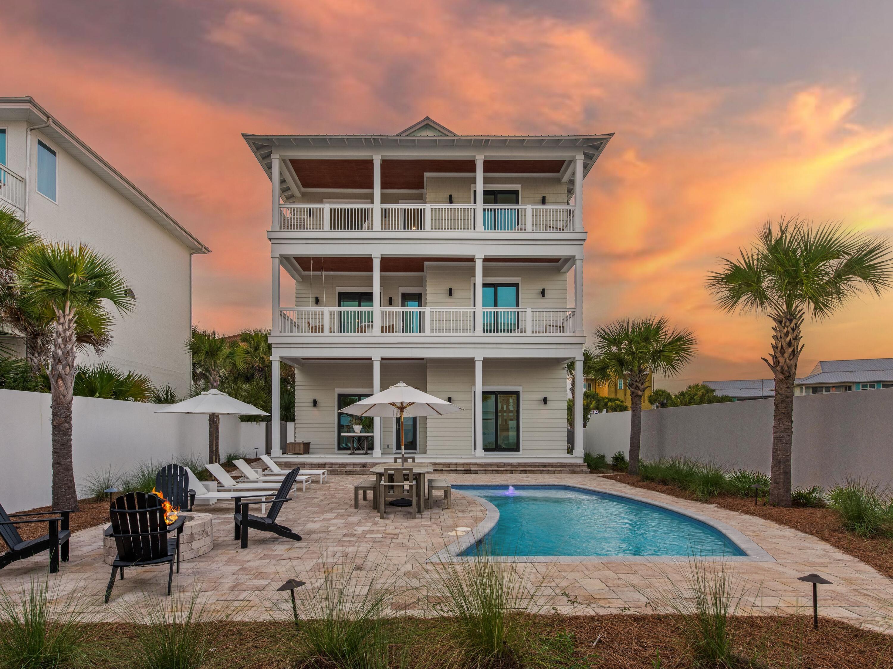 Few streets in Seagrove hold their ground the way San Roy Road does. Set one lot off the beach, the home sits close enough to the gulf to the south to draw its light and breeze, while Eastern Lake, one of the region's rare coastal dune lakes, curves in from the north, so the water frames the property from two directions and the horizon never fully closes. Over the past several years, this street has drawn some of the area's most considered new construction; this three-story residence stands among the finest of them. Set behind a palm-lined paver drive, the home reads as clean coastal contemporary: crisp clapboard, a standing-seam metal roof and stacked verandas that step toward the water. The interiors are the real event. They are knockout high-end without ever tipping into excess, exceptionally tasteful and precisely judged, nothing overdone and nothing left wanting. Spanning more than 5,200 square feet, the home offers six bedrooms, five full baths and two half baths, with pecky cypress running as a quiet through-line, worked into cabinetry and ceiling detail on nearly every level, its texture warming rooms that are otherwise bright, white and unhurried. Because the gulf-front lots directly ahead are already built, the water views from inside are effectively permanent, the kind of forever views no future construction can take away.

The heart of the home is the second-level kitchen, a massively scaled space built for real cooking and real gathering, anchored by a waterfall-edge island, Sub-Zero refrigeration, a professional-grade range and custom cypress cabinetry. Walls of glass open it to the covered porches and the gulf beyond, and wide-plank white oak runs underfoot. Down on the pool level, a second full kitchen handles poolside entertaining on its own, so the lower floor never has to borrow from the one above. Marble baths, a built-in bunk room and multiple living areas give the house room to hold family and guests at the same time.

Outside, the lot lives large. The backyard is genuinely expansive for the beach block, given over to a spacious private pool within a walled, planted yard and framed by multiple levels of covered decks and porches that trade gulf breeze for afternoon shade depending on the hour. Two separate single-car garages, each with its own overflow storage, handle the practical side of coastal ownership without asking the home to compromise.

The result is a finely outfitted residence in one of Seagrove's most prominent settings, and one that has never been rented, its finishes and furnishings kept in original, uncompromised condition. Turnkey, thoughtfully built and moments from the sand, the shops and the dining that define this stretch of the coast, it is the rare home that asks nothing of its next owner. On a street like San Roy Road, homes at this level of finish rarely stay available for long.