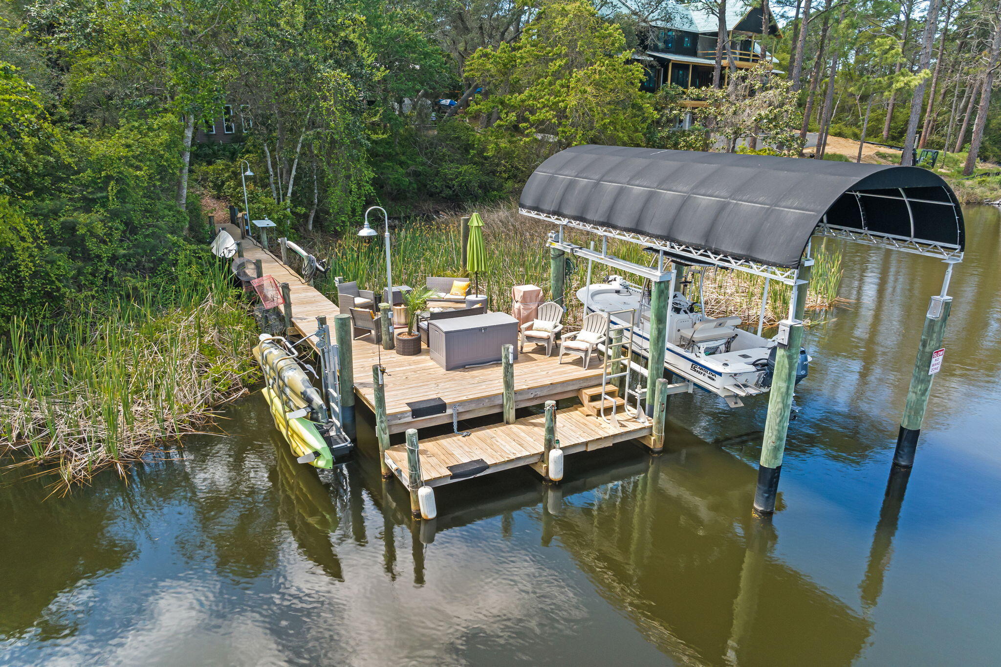 Welcome to 'Contentment,' where life on Lake Powell begins at your own private dock and extends all the way to the Gulf of Mexico. Located at 826 N Walton Lakeshore Drive in Inlet Beach, this remarkable waterfront property offers a lifestyle found in very few places along the Northwest Florida coast.

Spend the morning fishing the calm waters of Lake Powell, or take your skiff or kayak across the beach for quick access to the Gulf and return home with the day's catch. Wakeboarding, tubing, paddleboarding, kayaking, and kite surfing can all become part of the daily rhythm here. The lake is equally suited for quiet sunset cruises and weekends spent entertaining family and friends on the water. Despite its peaceful setting, the property is also just a short walk from the celebrated dining, shopping, and architecture of Rosemary Beach and Alys Beach.

Outdoor living unfolds across three levels. A ground-level patio leads to the newly resurfaced private dock, where generous gathering space creates a natural extension of the home. The dock is equipped with an outdoor hot-and-cold shower, a 5,000-pound boat lift with a custom heavy-duty aluminum-framed canvas canopy, and an elevated Seahorse double-kayak lift. Above, a screened porch off the main living area and a private upper-level deck provide additional places to relax, entertain, and take in the lake views.

The residence itself is as distinctive as its setting. Custom-designed over several years by architect Frank Greene, former Town Architect for Rosemary Beach, and completed in 2018, "Contentment" was conceived to maximize light, air, and space while blending relaxed coastal living with a refined industrial aesthetic. The home takes its name from the entry sculpture created by a local Inlet Beach artist.

Inside, the open-concept floor plan is defined by soaring ceilings, exposed wood and metal details, and painted floors with a well-worn patina that lends warmth and character. A handcrafted, three-story open stairway--constructed from the same structural beams that support the home--serves as a sculptural centerpiece. Four oversized pendant lights, retrofitted from industrial highway mast fixtures, anchor the main living area, while a wood-burning fireplace with a natural gas starter creates an inviting setting on cooler evenings.

Designed for those who genuinely enjoy cooking and entertaining, the kitchen features custom cabinetry with furniture-style bases, natural quartzite countertops, a raised island designed for comfortable preparation, dedicated knife and spice drawers, and a separate pantry and laundry room. Appliances include a new refrigerator and freezer, gas cooktop with downdraft ventilation, built-in oven, microwave, and an additional refrigerator and freezer on the lower level.

The entire upper floor is devoted to the private primary suite, which opens to its own deck overlooking Lake Powell. Each bathroom incorporates a custom art-tile installation inspired by celebrated graphic and wildlife artist Charley Harper, complemented by the home's signature glass-block showers. A lower-level safe room and storage area, along with generous attic and crawl-space storage, add exceptional functionality.

Currently configured as a one-bedroom primary residence, the home offers the opportunity to be thoughtfully reimagined as a three-bedroom retreat with relatively modest modifications, as illustrated in the accompanying conceptual images.

Additional features include impact-rated windows and doors throughout, a natural gas whole-house generator, a large Browning safe, low-maintenance landscaping composed of native plants, ground cover, and natural stone, and custom Rookwood tile artwork accenting the covered front porch.

"Contentment" is more than an architect-designed lakefront home--it is an invitation to experience one of the most unique lifestyles on the Emerald Coast, where boating, fishing, watersports, the Gulf of Mexico, and the communities of Rosemary Beach and Alys Beach are all within effortless reach.