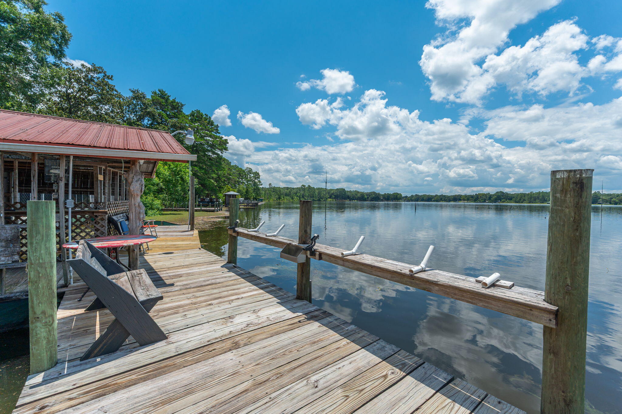 You must check out this waterfront retreat on beautiful Lake Juniper! This one of a kind property offers the perfect blend of comfort, recreation, and country charm, all just 10 minutes from town on a quiet, county maintained dead-end road. The beautifully renovated (around 2016) 3 bedroom, 2 bathroom home features a spacious living room centered around a huge wood burning fireplace, making it a great place to gather. Need extra space for guests or family? The charming 1 bedroom cabin overlooking the lake offers a private getaway, with its own full bathroom, living room, kitchen and storage closet, they will never want to leave! Situated on approximately ¾ of an acre, the fully fenced property is packed with extras that the outdoorsy types will fall in love with. Enjoy your own private slice of Lake Juniper living with a dock, covered boat slip, boat lift, and private boat launch. Just bring your fishing pole and boat! The dock also features an outdoor shower and a convenient fish cleaning sink, while the nearby bath house includes a shower and toilet, making lake days even easier. The outdoor fun doesn't stop there! Relax around the fire pit, entertain under the pavilion, tend to your favorite plants in the greenhouse, or pick fresh fruit from the property's numerous fruit trees, when they are producing. There's even RV parking with a 30-amp hookup plus water and septic access, making it easy to host family and friends. For hobbyists, boat enthusiasts, or anyone needing extra storage, the large powered workshop/garage with a loft provides endless possibilities. Add in the expansive paved driveway and all the room you need for vehicles, boats, and toys, and you've found a property that's ready for adventure. Whether you're searching for a full-time residence or weekend getaway, this special Florida escape offers the lifestyle most of us dream of! Appointment only! Contact your favorite realtor to schedule a showing.