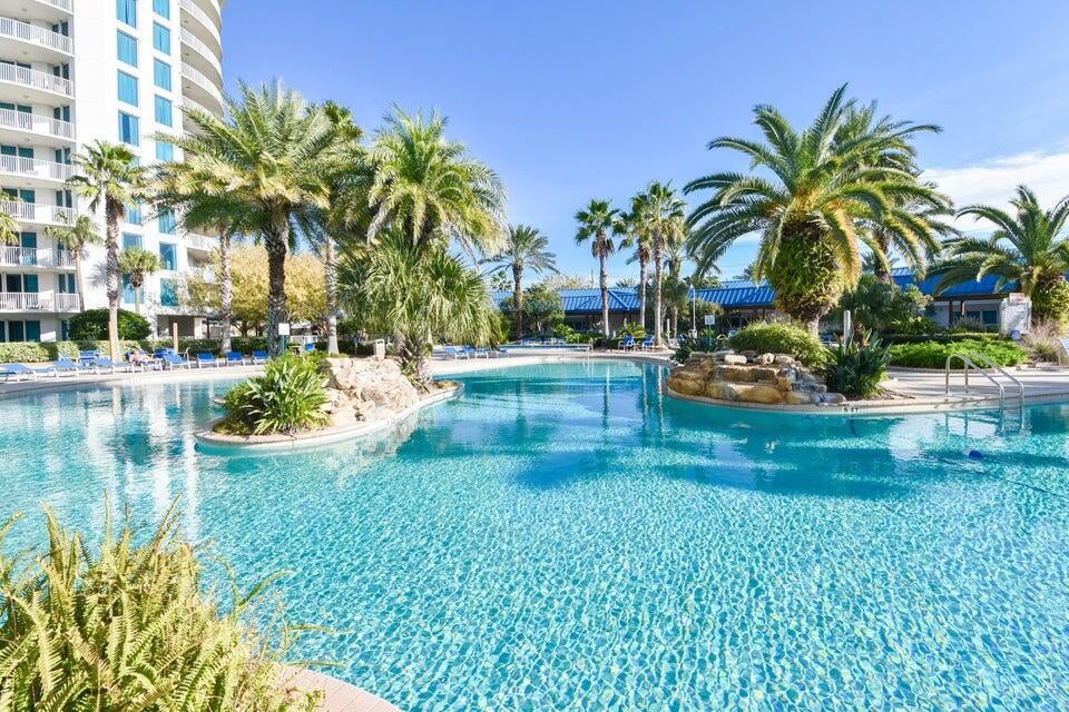 The Palms of Destin features an expansive 11,000-square-foot lagoon pool with a waterfall and spa, a children's pool, playground, and splash pad for endless family fun. Enjoy access to lighted Tennis and basketball courts, a state-of-the-art fitness center, and seasonal shuttle service to the beach. Additional amenities include covered, protected parking, an office center, and reception desk for your convenience. Association fees cover all utilities, including electricity, water, cable, internet, and local phone service, making ownership hassle-free.