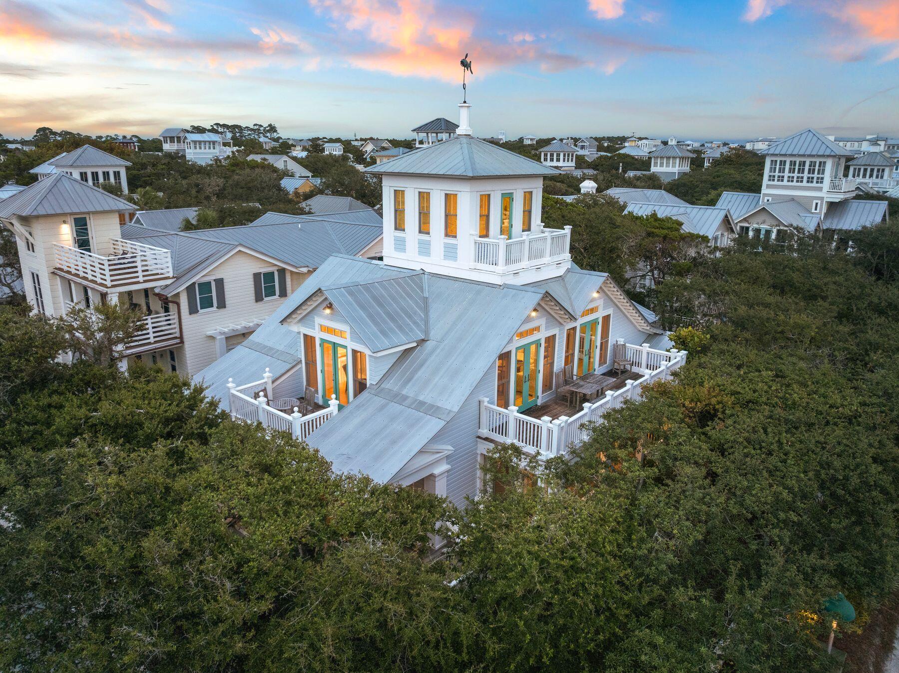 Sitting prominently at the corner of 30A and Natchez Street, this custom built and updated cottage occupies one of Seaside's most coveted locations, directly across from the beach and just steps from the beach walkover.
The full-width front porch, anchored by stout columns and a classic porch swing, wraps around the home and opens onto two of the bedrooms. Step through the foyer and the character of this beach cottage unfolds through board and batten walls, wood trim and wainscoting, and an inverted floor plan that places all four bedrooms on the first level and the main living space above.
The first floor features opens to a central hall leading to four bedrooms and three full baths. The king master retreat sits at the rear of the home for privacy, with a private en-suite bath featuring a separate tub and shower, plus a screened porch for a quiet retreat. A second king bedroom includes plantation shutters, a built-in closet with drawers, and an en-suite bath that connects to an outdoor shower. A third king bedroom offers a private closet and shares a Jack-and-Jill style bath with the fourth bedroom, currently configured as a queen, with both of these bedrooms opening onto the wraparound veranda. A hall laundry closet with washer and dryer adds convenience to the first floor. Stairs off the foyer lead to the second level living area, where oak flooring continues underfoot and peaked ceilings with exposed beams create a light, airy gathering space. Two linen slip-covered sofas with swivel club chairs anchor the living room, complemented by a half bath. The kitchen has been fully remodeled with Taj Mahal quartzite countertops, new cabinetry, a KitchenAid electric range and hood, KitchenAid refrigerator, and a panel-ready Thermador freezer with ice maker. Two dining spaces, an indoor banquette with storage and an outdoor eating area offer flexibility for entertaining, all framed by French doors and tall windows that shift the room's light and ambiance throughout the day. The home is offered fully furnished.
A spiral staircase leads to the enclosed tower on the third level, opening to a private deck with gulf views spanning east to west, capturing both town and water views.
Perhaps the greatest opportunity at 16 Natchez is what's still to come: approved plans already exist for an 800-square-foot, two-bedroom guest cottage on the property, offering a rare path to add meaningful square footage and value in the heart of Seaside.
Seaside is the town that started it all, the original New Urbanist community on 30A and the model for beach towns built for walking rather than driving. As Seaside's westernmost street, Natchez sits just before Watercolor begins, placing this home at the edge of two of 30A's most celebrated communities. This home sits directly across the street from the Natchez Beach Pavilion, one of Seaside's iconic sugar white sand access points, putting the Gulf within an easy walk from the front porch. From here, residents are close to the pedestrian paths and greenways that connect throughout town, as well as the shops, restaurants, and open air markets of Seaside's central square.
