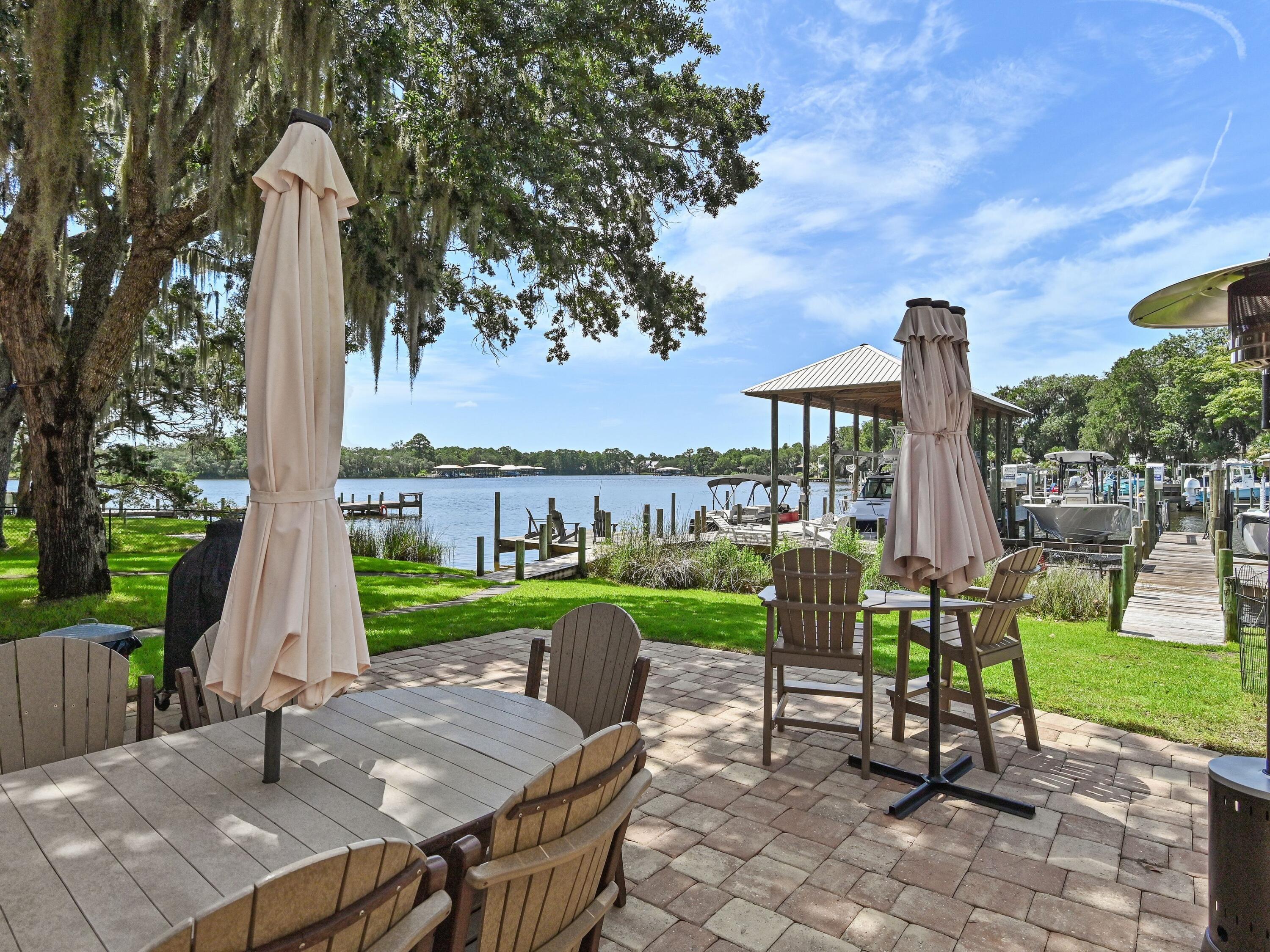 Wake up each morning to peaceful waterfront views and end every evening with breathtaking sunsets that paint the sky in brilliant shades of orange, pink, and blue. From your private dock, you'll enjoy a front-row seat to one of nature's most spectacular shows as dolphins regularly swim through Mack Bayou, playing and feeding just offshore, while a majestic blue heron makes daily visits to fish from the dock. Whether you're sipping your morning coffee, unwinding with a glass of wine at sunset, or simply enjoying the sights and sounds of the water, this home offers an ever-changing display of coastal wildlife and the relaxed waterfront lifestyle you've been dreaming of. Deep-water dockage, open bay views, and exceptional coastal living await at this beautifully maintained waterfront townhome on Mack Bayou in Santa Rosa Beach. Nestled within an exclusive enclave of only four residences, this exceptional 2-bedroom, 2.5-bath home offers approximately 1,600 square feet of thoughtfully designed living space along with the rare opportunity for both personal enjoyment and investment, as short-term rentals are permitted. Situated on 100 feet of shared bayou frontage with expansive open bay views, each residence enjoys a shared 40-foot dock, dedicated boat slip, and boat lift. With approximately four feet of water depth year-round, the slip easily accommodates larger boats, allowing you to spend more time on the water and less time worrying about the tides. A convenient fish-cleaning station makes returning from a successful day on the water effortless, and the seller's 26-foot boat, currently housed in the slip, is available for purchase separately. Inside, natural light pours through an impressive, oversized skylight, illuminating the open-concept living and dining areas. The custom kitchen was designed with entertaining in mind and features solid wood shaker cabinetry with soft-close doors and drawers, a wet bar, beverage refrigerator, and refrigerator with in-door water and ice dispenser. The spacious waterfront primary suite offers a peaceful retreat with sliding glass doors leading to a private balcony overlooking the bayou. Even the primary bathroom embraces the waterfront setting, featuring dual vanities and tranquil water views that make every day feel like a vacation. Outdoor living is equally impressive with expansive brick-pavered front and rear porches, an outdoor shower for rinsing off after a day on the boat or at the beach, and both front and rear storage rooms perfect for fishing gear, paddleboards, beach equipment, and more. The front porch even includes a dedicated water supply for potted plants and seasonal flowers. Quality craftsmanship is evident throughout with hardwood flooring on the main level and staircase, new luxury vinyl plank flooring upstairs, solid-core interior doors, elegant 8-inch baseboards, a Tesla electric vehicle charger, heavy-duty stair handrail, new fencing, a new electrical panel, and a recently replaced well pump. Major improvements provide added peace of mind, including a 2017 roof, 2022 18 sear Mitsubishi true variable air conditioner / heat pump, 2020 water heater, and a brand-new community septic tank and drain field installed in 2025. Owners share the cost of lawn maintenance, pest control, common area irrigation, water and electricity to the docks, and umbrella insurance for the building, allowing for a convenient, low-maintenance waterfront lifestyle. Two dedicated parking spaces are located directly in front of the residence, and the prime Santa Rosa Beach location places you just minutes from the sugar-white beaches of Scenic Highway 30A, Grand Boulevard, Sacred Heart Hospital, premier shopping, dining, golf, and entertainment. Whether you're searching for a primary residence, a second home, or an income-producing investment, this rare waterfront offering combines deep-water boating, private boat slip and lift, spectacular sunsets, abundant coastal wildlife, and an unmatched waterfront lifestyle in one truly remarkable property.