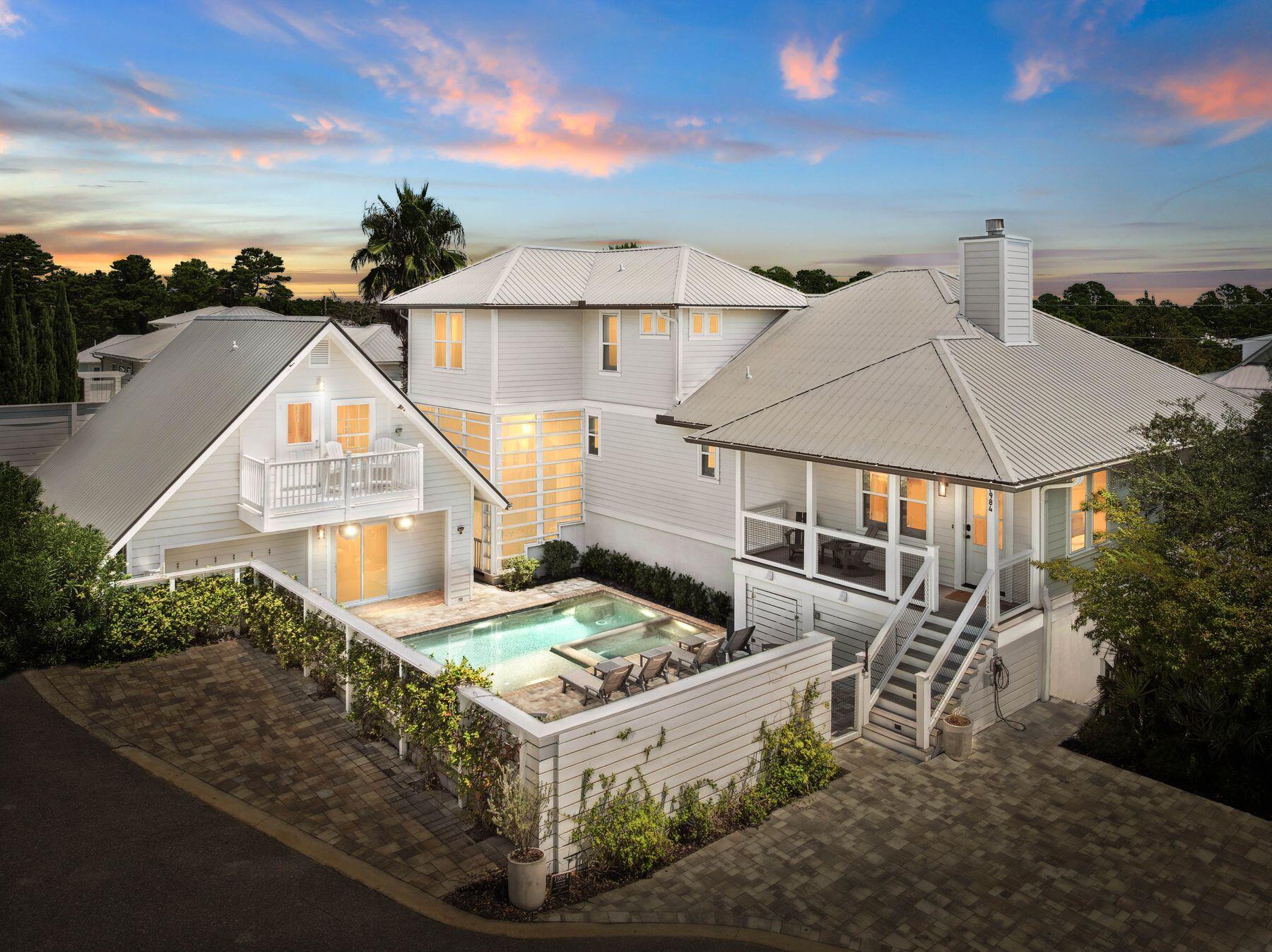 This exceptional seven-bedroom, six-bath residence is thoughtfully designed to accommodate every lifestyle, whether as a full-time family home, a vacation retreat, or a multi-generational gathering place. Situated just moments from the sugar-white sands of the gulf, it offers a private pool, carriage house, and two additional lock-out units, providing unmatched flexibility for owners and guests alike. Inside the main house, light-filled living spaces are framed by minimalist white walls, warm wood accents, and graceful crown molding. Wide-plank flooring leads toward the heart of the home -- a striking kitchen anchored by a vast island and bar with seating for five.