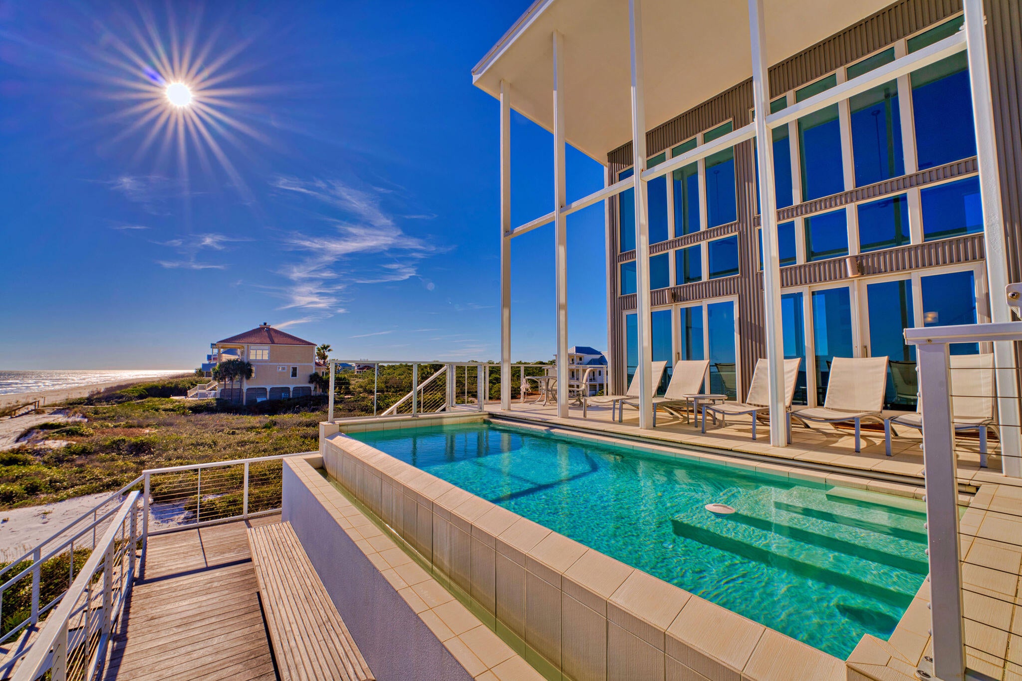 Welcome to Sugar Sands Sanctuary, an exquisite Gulf front legacy home nestled in the gated community of The Plantation on St. George Island. Designed by renowned architect Carey McWhorter, this contemporary masterpiece spans over 5,000 square feet and boasts 100 feet of stunning beachfront on the Gulf of Mexico. From the moment you arrive, you are greeted by covered concrete parking and a spacious, enclosed foyer with an elevator for convenience. The first floor features an open living/dining/kitchen area with soaring two-story ceilings and walls of glass that provide breathtaking Gulf views. The elegant and serene decor, combined with comfortable seating, a flat-screen TV with a home theater system, and direct deck access, creates the perfect atmosphere for relaxing and entertaining.
The chef's kitchen is a culinary dream, equipped with designer stainless appliances, double ovens, two refrigerators/freezers, quartz counters, custom cabinetry, a large pantry, and a separate breakfast bar. Mealtime is a delight with ample seating at the large dining table and breakfast table, both offering stunning views of the Gulf as a backdrop for unforgettable memories.
Step outside to the expansive deck space, where you will find an amazing infinity pool elevated above the dunes and overlooking the Gulf of Mexico. The outdoor living area is beautifully furnished with lounger chairs and tables, providing the perfect setting for al fresco dining and enjoying the Gulf breezes.
 Sleeping accommodations on the first floor include the NE king primary bedroom with a private balcony and flat-screen TV, the East king primary bedroom with a private balcony and flat-screen TV, and a bunk bedroom with two bunk beds (full/full and twin/twin), a flat-screen TV, and an attached full bathroom. The second floor features an interior balcony overlooking the living area, a desk/workspace ideal for remote work or study,                                                                          and additional luxurious sleeping quarters.
The SE king primary bedroom on the second floor offers an enormous walk-in shower, soaking tub, private deck access, flat-screen TV, stunning Gulf views, and a private sitting area. Additional sleeping accommodations include the NE king primary bedroom with a private balcony and flat-screen TV, and the East king primary bedroom with a private balcony. Both the first and second floors have laundry areas with washers and dryers,                                                                               and an additional full bathroom on the first floor for added convenience.
This turnkey home is beautifully furnished and ready for you to move in. With concrete and steel construction, it is built to withstand hurricanes and offers generous storage inside and out. The expansive outdoor spaces and gorgeous views from every room make this family home perfect for beach living and entertaining.
Sugar Sands Sanctuary is not just a home; it's a lifestyle. Enjoy exclusive community amenities, including tennis courts, a fitness center, nature trails, bicycle paths, and access to Nick's Hole Cove and Apalachicola Bay. Located near island shops, restaurants, nightlife, and the St. George Lighthouse Museum, this secluded and serene sanctuary offers the best of the Forgotten Coast within easy reach.
Experience luxury, comfort, and timeless memories at Sugar Sands Sanctuary. This is your opportunity to own a piece of paradise on St. George Island.