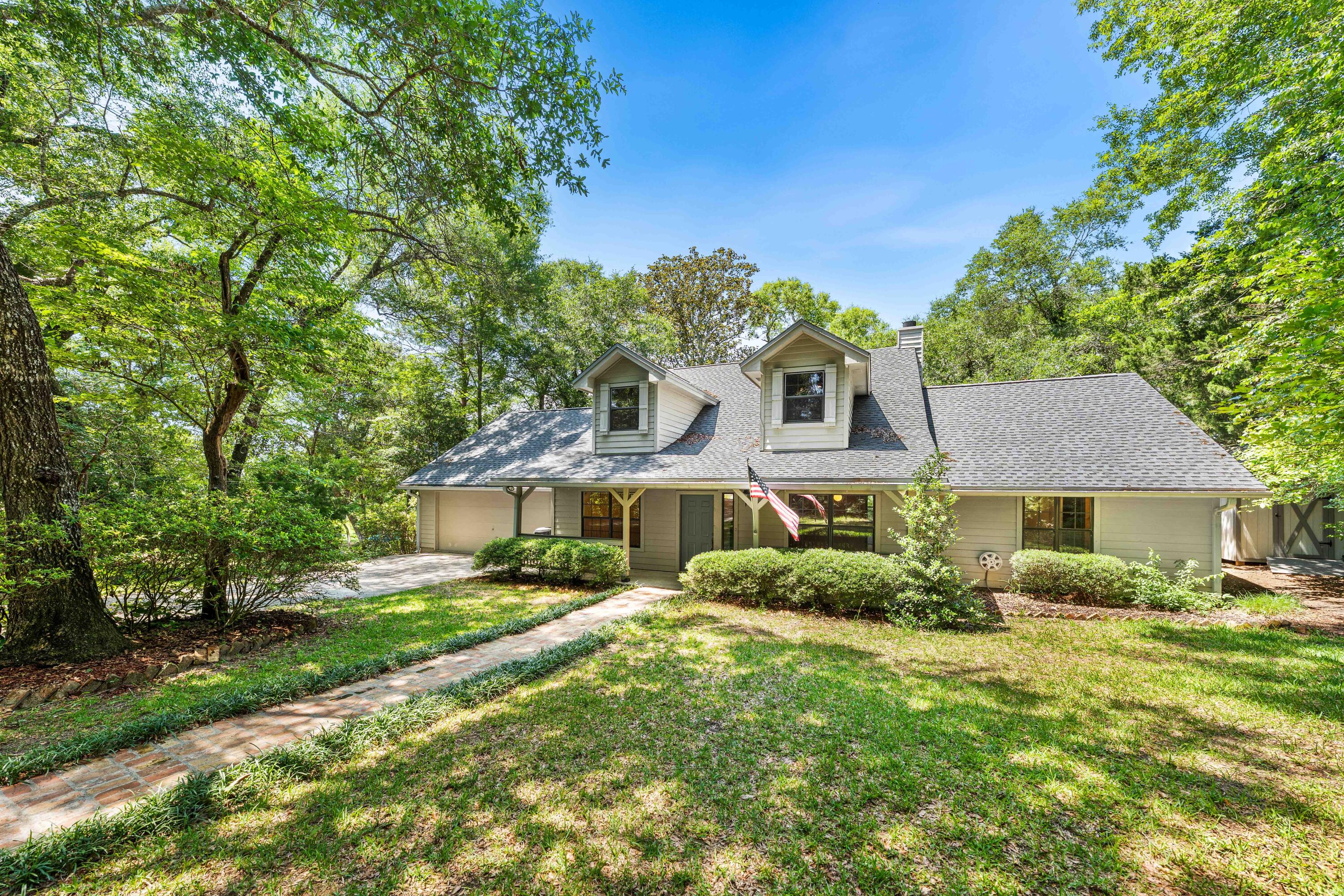 Nestled on a beautiful, oversized lakefront lot in the desirable Lake Sharon Estates community, this charming Southern-style home offers peaceful waterfront living surrounded by majestic oak and pine trees and lush, mature landscaping. Enjoy the tranquility of the lake from the spacious rear deck, where you can watch local wildlife and take in breathtaking water views year-round.
Ideally located just minutes from Niceville and the Mid-Bay Bridge, this home provides convenient access to the white-sandy beaches, dining, shopping, and entertainment of Destin while maintaining a quiet and private setting. Inside, the home features a spacious and welcoming floor plan designed for comfortable living and entertaining. A large sunroom overlooking the lake has been enclosed and incorporated into the main living area, creating an expansive gathering space filled with natural light and stunning waterfront views. Whether relaxing with your morning coffee or hosting family and friends, this extended living area offers a beautiful connection to the outdoors.
The primary suite, an office, and a private guest room and full bath are conveniently located on the first floor. Upstairs, two generously sized guest bedrooms share a Jack-and-Jill bath, providing ample space for family and visitors. With its scenic lakefront setting, majestic trees, abundant wildlife, spacious living areas, and exceptional location, this home offers the perfect blend of Southern charm, privacy, and convenience. Photos with furniture are virtually staged.