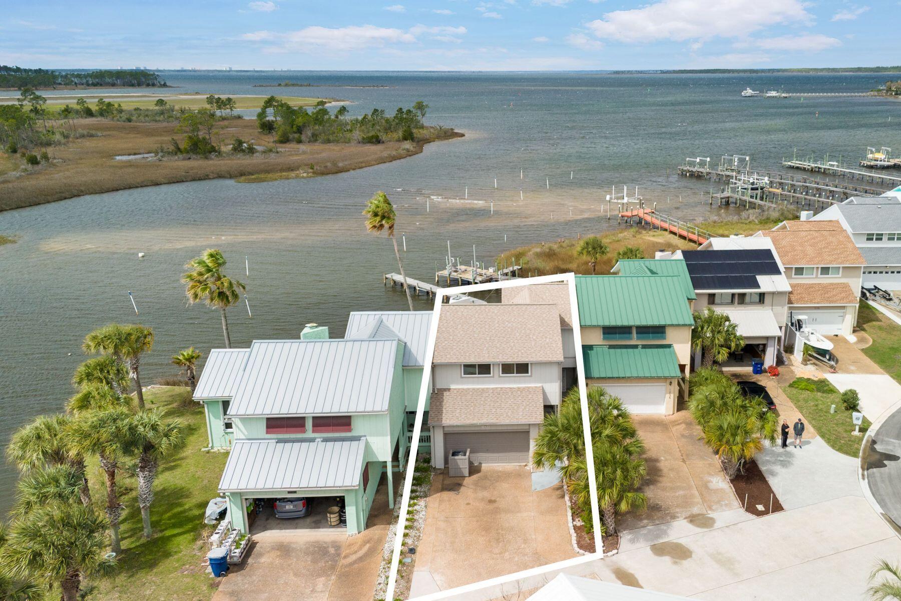 Waterfront living becomes remarkably attainable in this expansive bayfront townhome, where sweeping views, an impressive private dock and a rare no-HOA setting create a unique opportunity at this price point. Soaring cathedral ceilings elevate the great room, complete with an electric fireplace and dramatic second-story vault. Natural light pours through etched glass accents and a wall of windows overlooking the bay. The kitchen features Italian porcelain tile and comes fully equipped. A Florida room flows into a screened sunroom and a spacious deck, ideal for entertaining or relaxing. Outside, an 85-foot private dock invites kayaking, fishing or sunset views. With three bedrooms, 2.5 baths, a two-car garage and a charming front porch, this home blends space, character and true bayfront li