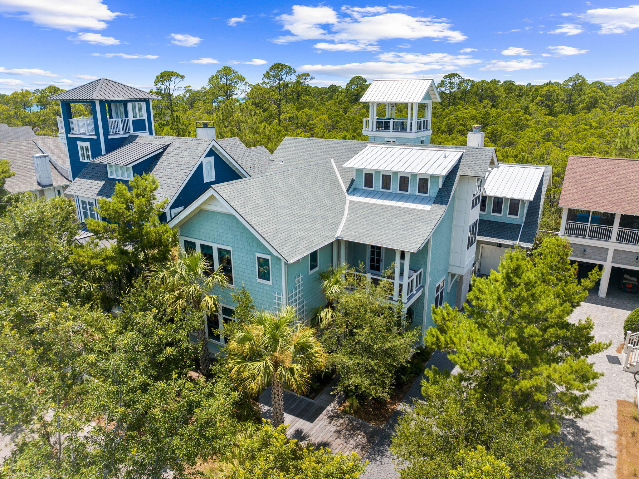 Welcome to 58 Coopersmith, a unique offering within the gated confines of Watersound Beach. Backing up to Deer Lake State Park, the location marks the perfect setting for this custom built home featuring elements not seen in its surrounding neighbors. The New England architecture blends perfectly with rustic elegance. Such features include solid hand-hewn beams accenting various areas of the home and holding center stage in the open floorplan living/dining/kitchen area, custom reclaimed wood floors throughout the home, and various ceiling and wall accents of reclaimed barn wood and pecky cypress. Truly an entertainer's dream, the main level was designed to merge indoor and outdoor living by simply opening the nano doors from the living area to the backyard oasis. There you will find a Miami inspired pool with illuminated steps and waterfalls leading to a covered patio area with outdoor kitchen, fireplace, and built-in pizza oven. Adjacent is another accordion style door opening to a game room with a ping pong table, bar with kegerator and multiple tv's along with a full bath. Barn style doors connect this room to the garage. Moving back into the main living level of the home you will find a kitchen designed for a true culinary connoisseur. An illuminated crystallo countertop showcases the kitchen island surrounded by a lavish appliance package including a Wolf 6 burner range, large Sub-Zero refrigerator, and a pantry area with an Irinox blast chiller and vacuum sealer. Adjacent to the kitchen area is an additional wet bar with a standup wine cooler. The living room is complemented by the beautiful gas fireplace and immense natural light. The main level also includes a powder room, laundry area with reclaimed barn doors, and one of the two master suites complete with an astonishing bathroom. Choose either the 3 stop elevator or the custom designed staircase to take you upstairs to the second floor where you will find another master suite, 2 guests suites, living room, powder room and wet/coffee bar. The primary suite on this floor has its own wet bar, vaulted ceilings with hand hewn beams, walk-in closet and luxurious bathroom. The 2nd floor living area leads you out to the deck connecting you to the only free-standing tower in Watersound, complete with multi-floor patio areas leading to the top where you can take in the Gulf views. Above the garage is a separate apartment area currently being used as a theatre room with electric roll down shades and projector screen. A murphy bed is integrated for those extra guests. The 3rd floor is designed for the little ones, featuring a multitude of large bunks and built-ins and topped off with an amazing bath with a reclaimed wood beam vanity. Watersound Beach offers pristine amenities and is situated in the heart of 30A. Enjoy some of the most scenic views in our area from the boardwalks leading across the preserved dune structure taking you to the large stretch of private beach.