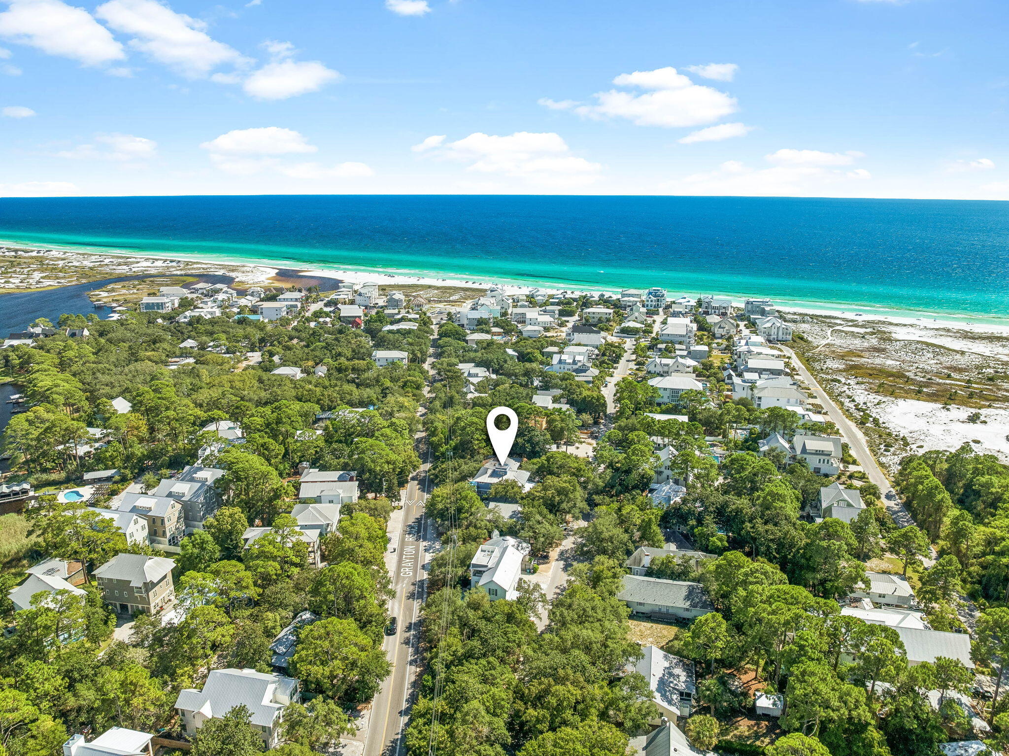 Tucked beneath a canopy of live oaks in the heart of Grayton Beach, this elevated five-bedroom home is positioned a short distance from the beach as well as the Red Bar and a number of other shopping and dining opportunities. The main living level is open and airy, with elevated ceilings, wood floors, and designer fixtures all anchored by a grand fireplace. The area flows seamlessly from the living room into a dining area.  A chef's kitchen features a gas range and a butcher-block island with bar seating. An expansive balcony extends the living space outdoors. The primary suite located on this level offers an ensuite bath, large closet and its own private balcony. On the upper level,  three more bedrooms, two bathrooms, a laundry room, and a family room are all perfectly positioned. A spiral staircase from the family room leads to the rooftop lookout, with treetop views over the Gulf of Mexico. The ground level adds a fifth bedroom and a flex room that granting access to the courtyard oasis. Outdoors, a brick-paver courtyard holds a private pool, a covered dining pavilion, and an outdoor shower. Parking includes covered space for a golf cart. Beaches, Western Lake, and the 30A bike path are nearby. Do not miss the rare opportunity to own a piece of Grayton Beach!