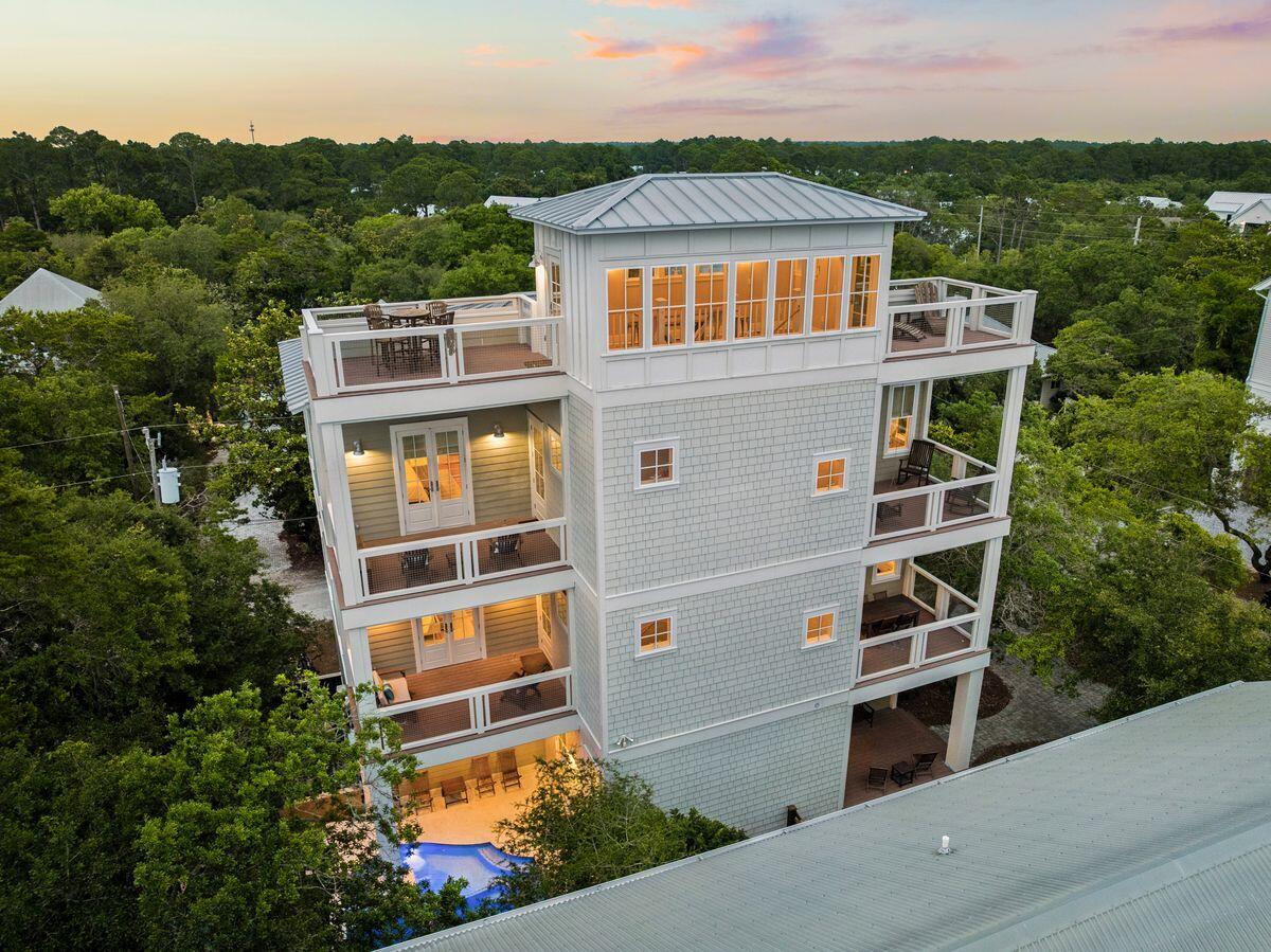 Seagrove Magnolia offers a rare combination of modern construction and mature surroundings in the heart of Old Seagrove. Built in 2016 and arranged across four levels, the 4,166-square-foot home was designed for the way families gather, entertain, and return to 30A year after year. Multiple living spaces, expansive porches, and private bedroom suites create a residence that functions equally well as a beach retreat or full-time home.
Arrival begins with a circular drive framed by mature landscaping and a front porch finished with natural wood ceilings and flooring. Inside, oak floors, tall ceilings, and warm natural materials create an atmosphere that feels established and welcoming. The first floor functions almost as a private residence within the home, complete with its own exterior entrance, full kitchen, living area, king bedroom, bath, and laundry area. Whether accommodating extended family, long-term guests, or multiple generations under one roof, the space offers a level of independence rarely found in a traditional beach home. The second floor serves as the center of daily life. An open-concept kitchen, dining area, and living room connect seamlessly to the surrounding porches. Anchored by a Bertazzoni gas range and hood, generous pantry storage, and premium appliances, the kitchen was built to support extended stays and large gatherings. A king suite on this level offers the convenience of single-level living adjacent to the home's primary gathering spaces, while an office area and a full laundry room with sink, storage, and additional ice maker support both everyday living and extended stays.
The third floor introduces another gathering space with a casual living area, game table, and porches on both sides of the home. Two king bedrooms and a bunk room with four extra-long twin beds create comfortable accommodations for family and guests, while the layout allows different groups to occupy the residence at the same time while maintaining privacy and separation.
Outside, the recently refreshed pool area serves as a private backyard retreat surrounded by mature vegetation. Covered lounging areas provide welcome shade, while artificial turf, a putting green, and a built-in gas grill connected to inline gas service create an environment designed for easy outdoor living. The setting reflects the character that has long distinguished Old Seagrove from newer coastal communities.
At the top of the home, a fourth-floor tower room provides one of the property's most memorable spaces. Finished with oak floors and wood ceilings, the room serves as a retreat above the surrounding canopy. Filtered Gulf views emerge through the trees and rooftops, while the open deck offers an elevated perspective that captures the unique landscape of Old Seagrove.
Beyond its architectural character, the home incorporates the practical systems experienced owners appreciate, including multiple HVAC systems, a dumbwaiter, fire suppression system, impact-rated windows, Neuma exterior doors, a standing seam metal roof, substantial owner storage, and an oversized garage.
Located approximately 300 yards from the Nightcap Street beach access and roughly one-half mile from Seaside's Town Center, Seagrove Magnolia places the beach, shopping, dining, and entertainment of 30A within easy reach. Offered furnished and supported by a strong rental history, the home presents an opportunity to enjoy the character of Old Seagrove while benefiting from the comfort and convenience of a newer home.