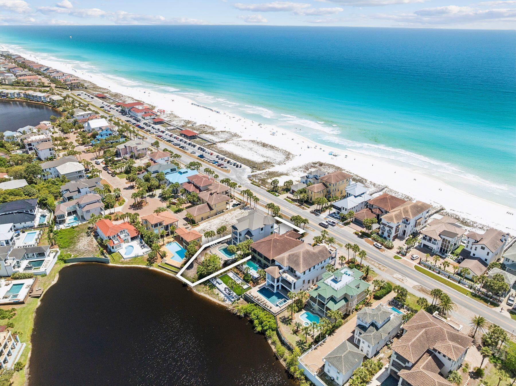 This extraordinary nine-bedroom estate offers a rare blend of architectural presence and resort-style amenities with commanding views of the Gulf and a serene coastal lake. Positioned directly across from a sprawling beach access, the home captures sweeping vistas of sugar-white sand and emerald waters from multiple levels, while the rear elevation opens to a tranquil tropical lake backdrop creating a truly unique experience. Extensively renovated and professionally designed, the residence spans approximately 6,000 square feet combining lasting quality with refined coastal style. Designed for both luxury living and exceptional rental performance, the home comfortably accommodates large groups with seven private suites and two expansive bunk rooms thoughtfully integrated into a highly functional floor plan. The first level is tailored for entertaining and guest privacy, featuring two king suites, two oversized bunk rooms with custom queen-over-queen accommodations, a shared bath, laundry area, and a secondary living space with wet bar that opens seamlessly to the pool deck. Outdoors, a resort-style heated pool anchors the experience, complemented by a covered summer kitchen, bar seating, and ample lounge space overlooking the lake ideal for gathering after a day at the beach. The second level serves as the heart of the home, where an expansive open-concept living, dining, and kitchen area is framed by panoramic Gulf views and extends onto a generous covered balcony. The chef's kitchen is equipped with premium appliances, custom cabinetry, a large center island, and walk-in pantry, designed to accommodate both everyday living and large-scale entertaining. Two additional guest suites with private baths complete this floor, along with convenient access to the outdoor living areas below. The top level features three well-appointed bedrooms, including dual primary suites with private balconies, spa-inspired bathrooms, and elevated Gulf views. A third king suite and additional laundry complete the level, offering comfort and privacy for owners and guests alike. A commercial-grade elevator services all floors, ensuring effortless accessibility throughout. Additional highlights include multiple indoor and outdoor living areas, surround sound, ample parking for up to eight vehicles including a two-car garage, and strong income-producing potential in a highly sought-after coastal corridor. With its commanding presence, thoughtful design, and unparalleled proximity to the beach, this exceptional property represents a rare opportunity to own a true legacy home along Scenic Highway 98.