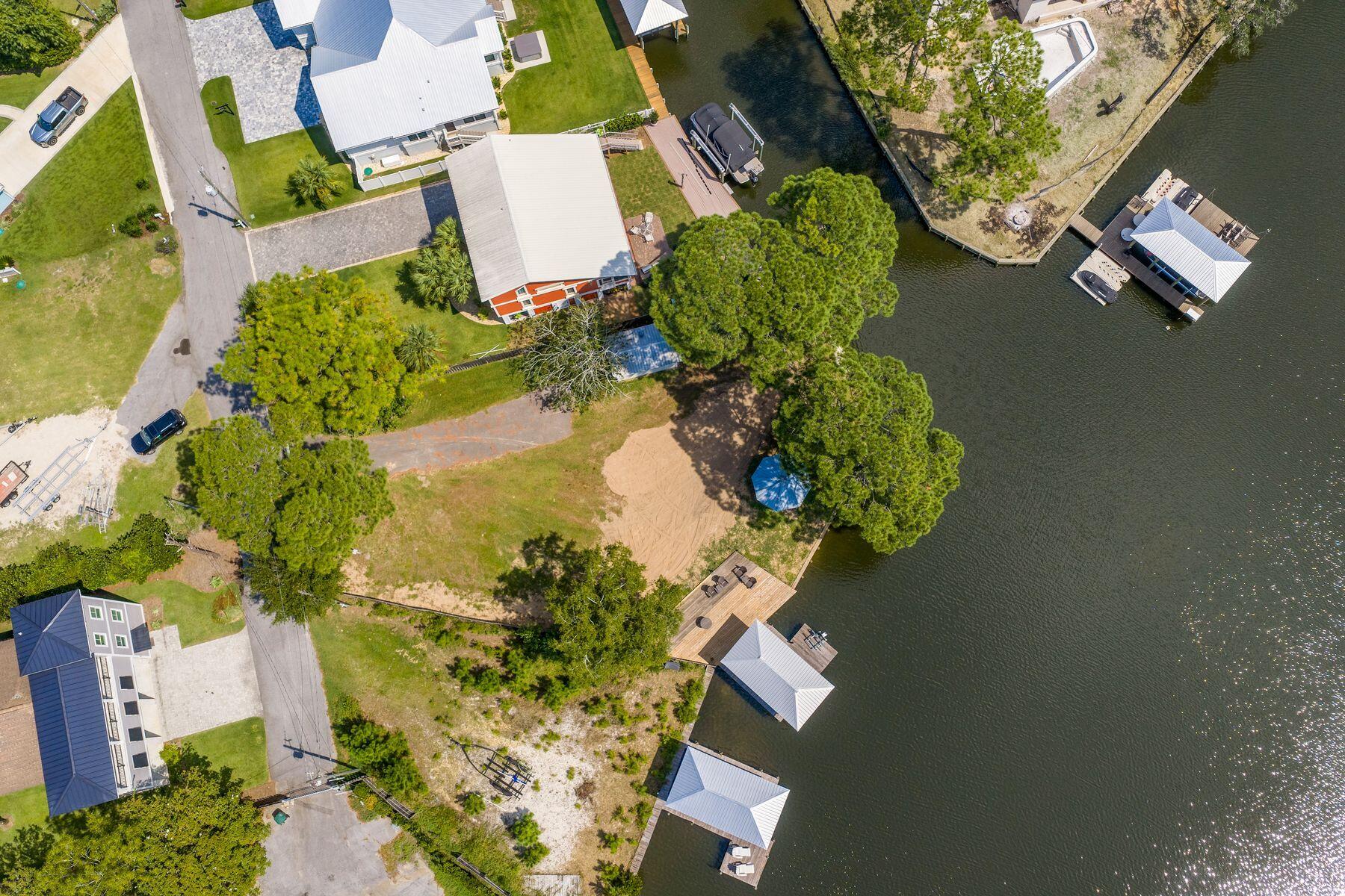 Majestically gated and surrounded by estate homes, this premiere deep water homesite in Hidden Harbor offers 153 feet of waterfront on Buck Bayou. This serene and private setting is located just 300 yards from Choctawhatchee Bay, providing an ideal canvas for construction on a site that is already cut, cleared, and ready for development. The property is fully equipped with a new bulkhead, a dock, and a boathouse featuring a boat lift. Additional on-site amenities include two storage buildings, one of which is conveniently plumbed for a bathroom. It is situated just minutes from the crystal blue gulf waters of the 30-A beaches.  Premier dining, medical facilities, and the Shops of Grand Boulevard are located just down the street. This site offers a rare opportunity to custom build your home and live the dream lifestyle on Florida's Emerald Coast.
