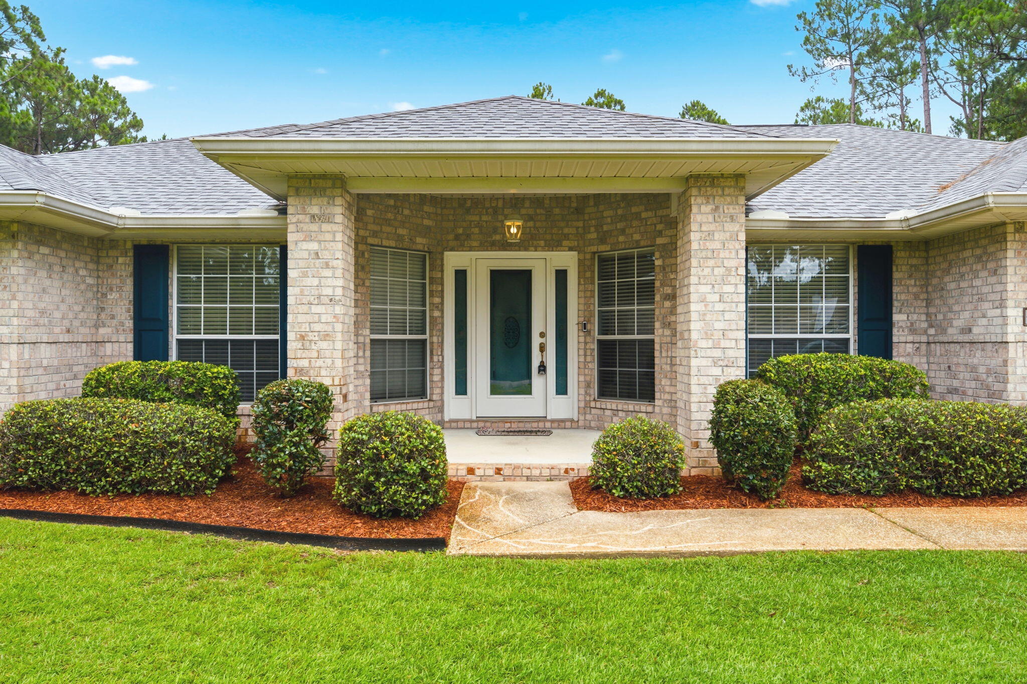 Welcome to 2386 Sherwood Drive in the highly desirable Holley By The Sea community! This beautifully maintained brick home offers a thoughtful combination of recent major updates, quality finishes, and outdoor space that's becoming increasingly difficult to find. Buyers will appreciate the peace of mind provided by a new roof (2023), water heater (2023), and HVAC system (2022).

From the moment you arrive, you'll notice the exceptional curb appeal. A matching brick mailbox, surrounded by mature shrubs and palm trees, creates a welcoming first impression and enhances the home's attractive exterior. The property sits on a nicely elevated lot, providing excellent drainage and ensuring water does not stand around the home.

Inside, you'll find an inviting floor plan featuring granite countertops, additional custom kitchen cabinetry, marble bathroom countertops, custom closet upgrades, tile flooring in wet areas, and bamboo flooring throughout the living spaces and bedrooms--completely carpet-free living. The home has been meticulously cared for and is ready for its next owner to move right in. Step outside and discover one of this property's standout features--a spacious backyard with plenty of room to design and build the pool of your dreams. A mature tree line along the rear of the property creates a natural privacy buffer and a beautiful natural backdrop. The neighboring land behind the property remains buildable, offering flexibility while still maintaining a spacious feel. An irrigation well services the yard, helping keep both the front and back landscaping lush and healthy year-round. Gutters have also been installed to promote proper drainage around the home.

Additional conveniences include a septic system that was pumped and inspected in 2024, professionally maintained landscaping, and spare flooring, tile, and roof shingles that will remain with the property for future use. All kitchen appliances convey, and the washer and dryer are included as a bonus.

Located within the sought-after Holley By The Sea community, residents enjoy access to premier recreational amenities while benefiting from a home where many of the major mechanical components have already been updated. Offering a blend of comfort, functionality, privacy, curb appeal, and long-term value, this move-in ready property is an exceptional opportunity in one of Navarre's most established neighborhoods.