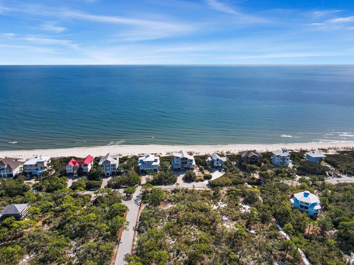An extraordinary homesite awaits just one block from the shoreline along Florida's Forgotten Coast. This rare one-acre, first-tier corner lot offers the scale, elevation, and privacy seldom found in such a premier coastal setting, providing the perfect canvas to design a custom retreat. Located within the gated St. George Plantation, this high, wide, and level parcel offers exceptional flexibility for architectural design and orientation. Its generous size allows for creative placement of living spaces to capture Gulf views while maximizing outdoor areas for pools, porches, and terraces. As one of the few first-tier lots of this size, it provides the freedom to build expansively without compromise. Situated in the desirable Pebble Beach Village section, the property is part of a thoughtfully planned residential community with architectural standards that protect long-term value and aesthetic integrity. The setting encourages a lifestyle centered around coastal breezes, open horizons, and natural beauty. Ownership includes access to outstanding Plantation amenities, including two community pools, tennis and pickleball courts, a clubhouse with fitness and gathering spaces, and scenic biking and walking trails. Private beach walkovers offer convenient Gulf access, and a direct path connects to St. George Island State Park. The gated entrance and 24-hour security provide added peace of mind. Large first-tier homesites within the Plantation are increasingly limited. This corner lot presents a rare opportunity to secure a premier coastal property and bring your vision to life in one of St. George Island's most sought-after communities.