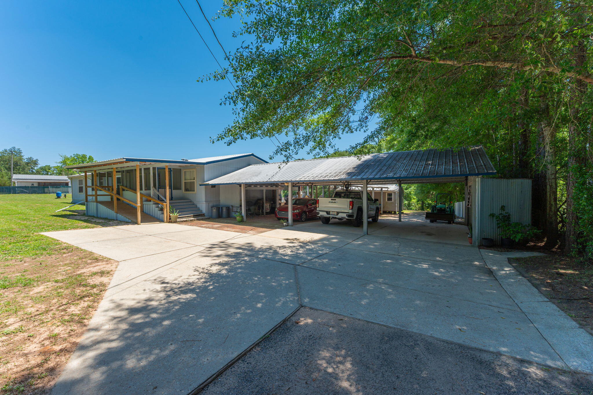Located on a full +acre in Baker, this property offers far more than just a home -- it's an outdoor lifestyle hub designed for entertaining, storage, recreation, and everyday convenience. The impressive 3-stall carport features a gas grill station with plenty of room for food prep, tables, and gathering with family and friends. On the opposite side, a dedicated utility and tool niche adds extra functionality. Behind the main parking area, an additional 2-stall carport provides covered space for recreational vehicles, boats, lawn equipment, or extra storage. RV owners will appreciate the covered RV pad complete with electric hookup and septic access.

Step inside through the spacious screened-in porch offering abundant seating space and room for a porch swing -- the perfect spot to relax and enjoy peaceful country living. Inside, the large living room welcomes you home, while three guest bedrooms and a full bath are located just off the main living area. Laminate flooring flows throughout most of the home, with carpet in the bedrooms for added comfort. The kitchen opens seamlessly into the dining area and features a breakfast bar, buffet area, and abundant cabinetry. The laundry room includes additional pantry and storage space. The primary suite boasts a huge walk-in closet, double vanities, and a large walk-in shower. Outside, the irrigated front lawn and frequent visits from birds and deer complete the peaceful setting. AS-IS SALE