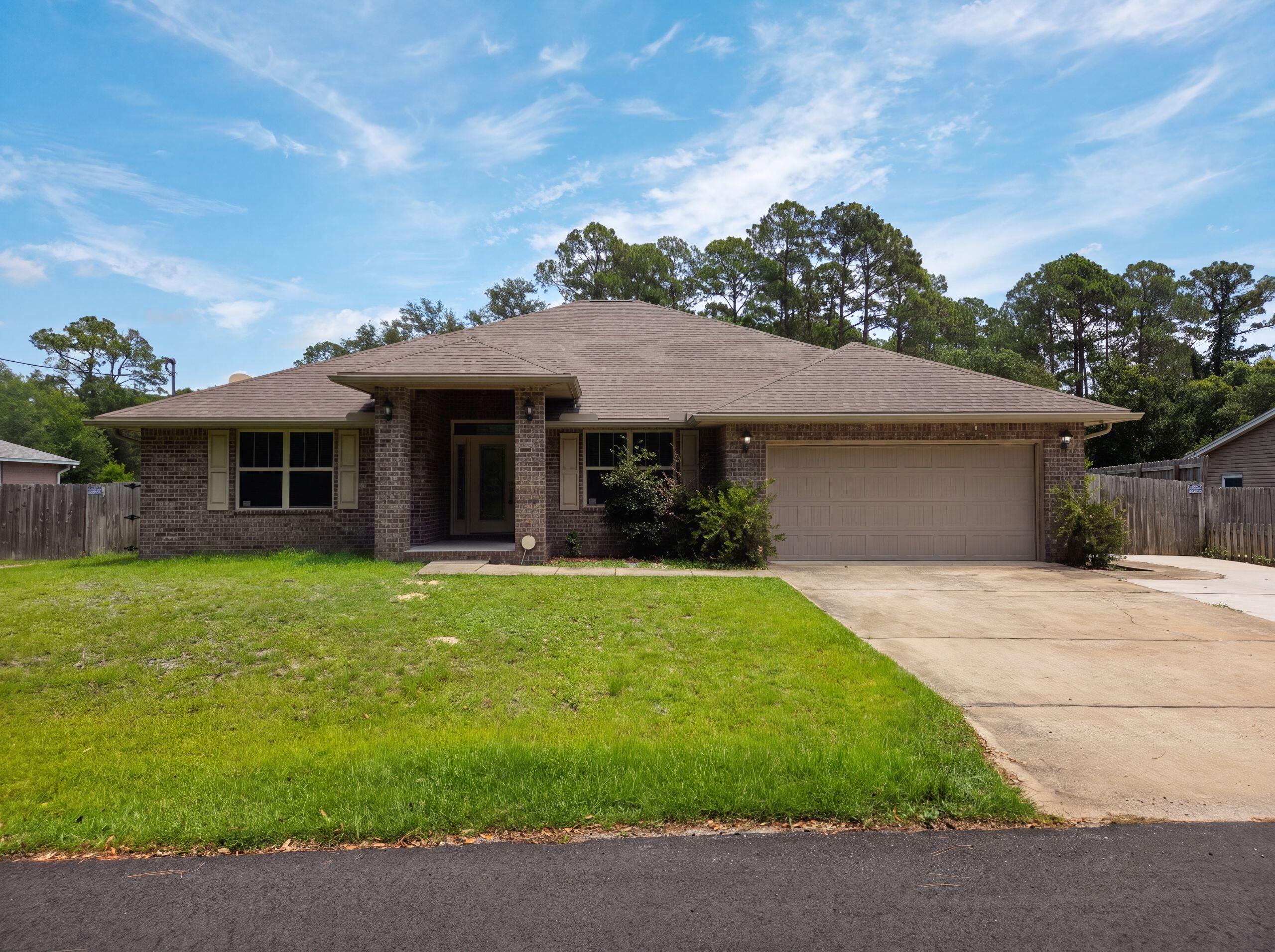 3054 Grady Tolbert Rd is a one-story Navarre home built in 2018. The kitchen centers on an island with a breakfast bar, paired with stainless steel appliances for prep and serving space. The adjoining living area runs across wood-look flooring for a connected main level. The primary bedroom features a tray ceiling, and its ensuite bathroom holds a soaking tub, a separate shower, and a double vanity. Outside, a covered patio overlooks a fully fenced backyard with room for outdoor use. A two-car garage adds parking and storage, completing a practical layout with functional spaces throughout the home.