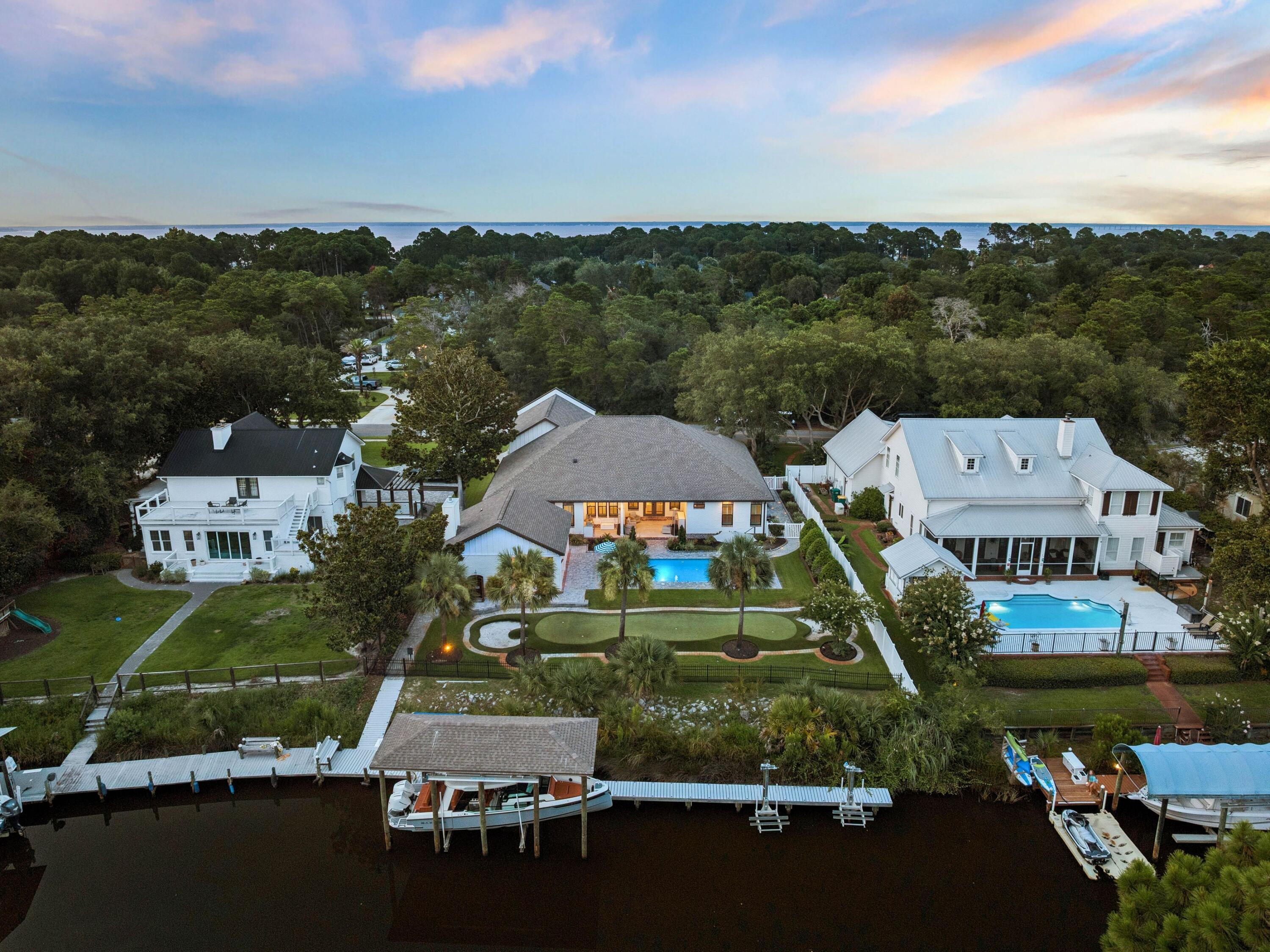 Every element of this extensively renovated waterfront residence has been thoughtfully curated to create an exceptional living experience where luxury meets effortless coastal living. Positioned along a quiet deepwater canal with direct access to Choctawhatchee Bay, this turnkey property offers the freedom of boating from your own backyard while remaining just minutes from the area's renowned beaches, golf courses, shopping and dining.

Inside, the open-concept floor plan is designed for both everyday comfort and entertaining on a grand scale. Wide-plank luxury flooring flows throughout the home, connecting spacious living and dining areas centered around a sleek gas fireplace with custom shiplap detailing. The chef's kitchen is equipped with premium Viking appliances and overlooks the main gathering spaces, while five generously sized bedrooms, four full bathrooms, two half baths and a dedicated office provide flexibility for families and guests alike.

The outdoor living spaces rival those of a private resort. A covered lanai with dual oversized ceiling fans, lighting and a fully equipped outdoor kitchen creates the perfect setting for alfresco dining, while the saltwater pool features a Baja shelf, tanning ledge, integrated lighting and expansive paver decking, surrounded by lush landscaping and privacy fencing. Beyond the pool, a custom putting green with chipping areas and a genuine sand trap offers endless recreation day or night thanks to thoughtfully placed accent lighting.

Water enthusiasts will appreciate the private dock, complete with covered boat and jet ski lifts, a 30-amp shore power connection, and an industrial-grade KillerDock cleaning station for effortless days on the water. A detached pool house with its own private entrance, living area, wet bar, and half bath offers exceptional versatility, serving equally well as a private guest retreat, hobby space, or seamless extension of the outdoor living area surrounding the pool.

Additional highlights include an oversized garage with ample room for vehicles and water toys, a whole-yard water softener, Generac generator, tankless water heater, irrigation system, landscape lighting and plantation shutters throughout. With no HOA restrictions and an unmatched combination of premium upgrades, exceptional outdoor amenities and direct boating access, this remarkable waterfront property offers a rare opportunity to enjoy the very best of the Florida lifestyle.