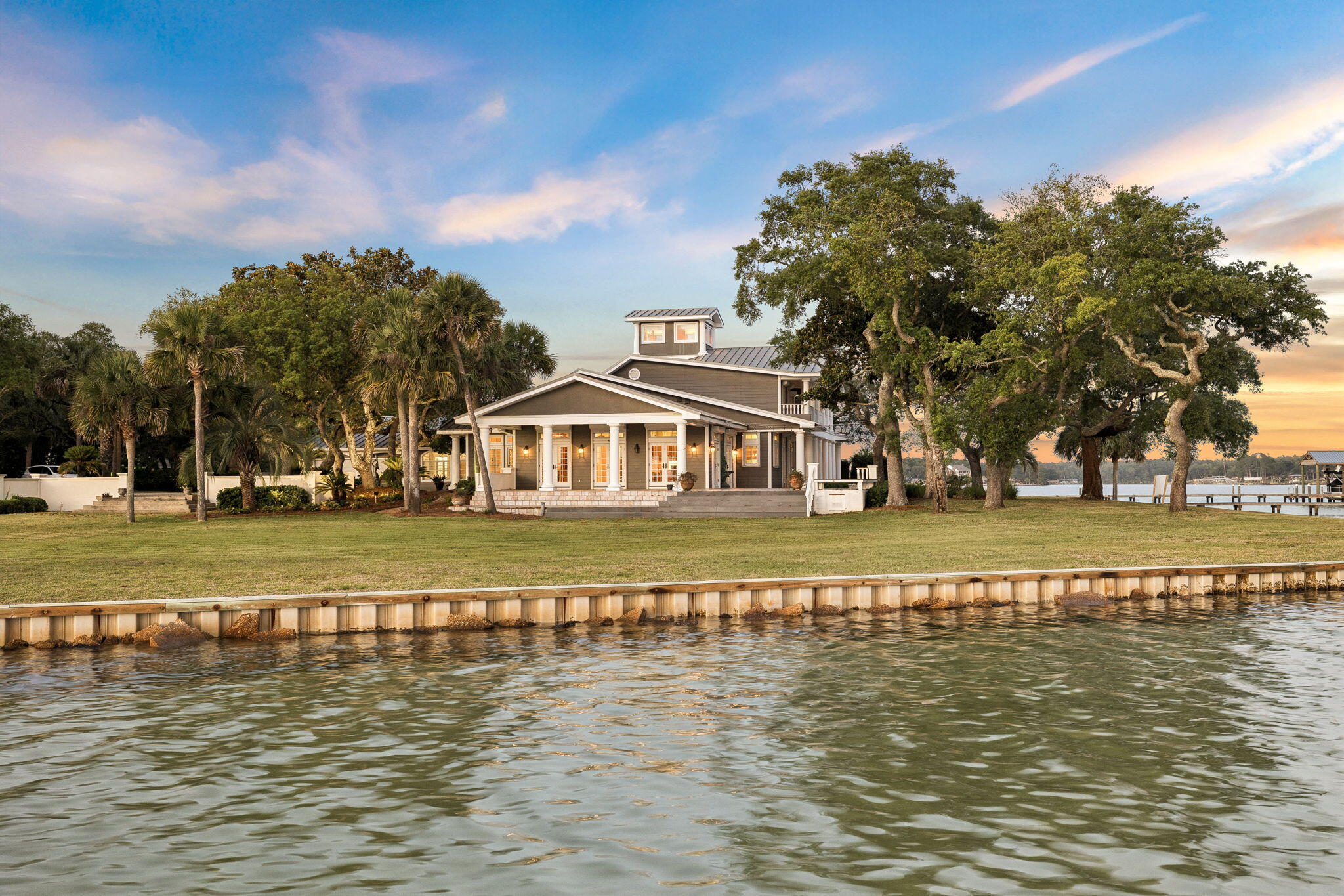 Few properties on Florida's Emerald Coast can claim what 11 Paradise Point Road delivers: a private covered boathouse with a full boat slip, over an acre of waterfront land, and direct access to Choctawhatchee Bay. Set at the corner where Garnier Bayou meets Poquito Bayou in historic Shalimar, this is the kind of lot that simply does not come available. Water on two sides, a seawall running the full length of the property, and a manicured lawn sweeping to the shoreline beneath a canopy of generational live oaks. The boathouse is deep, protected, and ready for daily use, whether that means a morning run to Destin Harbor, an afternoon on the open bay, an evening on the sandbar, or simply fishing off the dock at golden hour. For those who live on the water, this property was built for it. The setting carries history as well as beauty. Shalimar takes its motto from the water itself -- 'By the Beautiful Water' -- and the small bayou town has held to that founding character for nearly eighty years. Platted in the 1940s and quietly anchored along Garnier and Poquito Bayous, Shalimar has retained the same shaded streets and shoreline rhythm while the rest of the Emerald Coast grew up around it. Live oaks arch over the lanes, the gentle tides of the bayou shape the shore, and life here remains close to the water. The estate spans 6,591 square feet across three thoughtfully designed stories. A circular paver driveway winds through mature oaks and palms to a stately coastal Southern facade: grey board-and-batten siding, a standing seam metal roof, soaring white columns, and a covered wraparound porch finished in stone tile with open water views. Inside, a grand great room anchors the main level, with walls of French doors opening to the waterfront porch. Hardwood floors, beadboard ceilings, and crown molding carry throughout. The kitchen features granite countertops, warm wood cabinetry, and stainless appliances. A billiard room, formal dining space, and full laundry room complete the level. The primary suite offers direct bayou views, a soaking tub, and a walk-in shower. A sweeping second-floor balcony delivers panoramic views of both bayous. The third floor houses a private observatory above the treeline. Two gas fireplaces, multiple patio areas, a firepit, and attached garage complete this exceptional offering, all within close proximity to Destin and Fort Walton Beach.