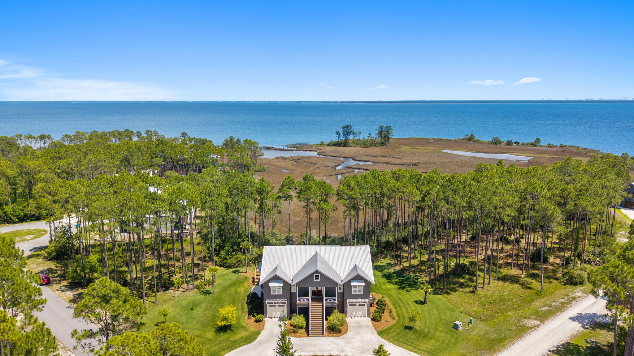 Overlooking West Bay with unobstructed water views, this custom-built residence is set on a premium 0.76-acre corner waterfront homesite with paved road access. The beauty of the setting extends indoors, where designer finishes and thoughtful details create a refined coastal home that feels both elevated and inviting. 

The kitchen serves as the centerpiece of the home, anchored by a Venetian plaster hood, Hallman Majestic gas range, quartz countertops, clay tile backsplash, open cypress shelving, and a dining nook featuring built-in bench seating with storage. A striking cypress beam connects the kitchen and living area, where a Venetian plaster fireplace serves as a focal point against a backdrop of sweeping water views. 

The primary suite serves as a true retreat and features scenic water views. The adjoining bath features Carrera marble finishes, polished nickel fixtures, an oversized glass shower and a freestanding soaking tub. Dual custom closets, including a dressing area with built-in vanity complete the suite. The expansive screened porch, complete with a gas fireplace, provides a breathtaking setting to relax and take in the views of West Bay. 

Thoughtfully designed landscaping complements the home's natural surroundings, with ample room for a future pool or addition. Additional features include an elevator, impact-rated windows, EV charging station, whole-home Generac generator, and finished split garages with abundant storage. RiverCamps offers a lifestyle unlike any other along the Emerald Coast. This private, gated waterfront community is bordered by West Bay and Crooked Creek, providing direct boating access to Shell Island and the Gulf. Residents enjoy dry boat storage, a community boat launch and day-use slips, a resort-style pool and pavilion, a 600-foot pier, miles of scenic trails and boardwalks, and a fitness center coming soon. Ideally located just minutes from Northwest Florida Beaches International Airport, Pier Park, and the area's white-sand beaches.
