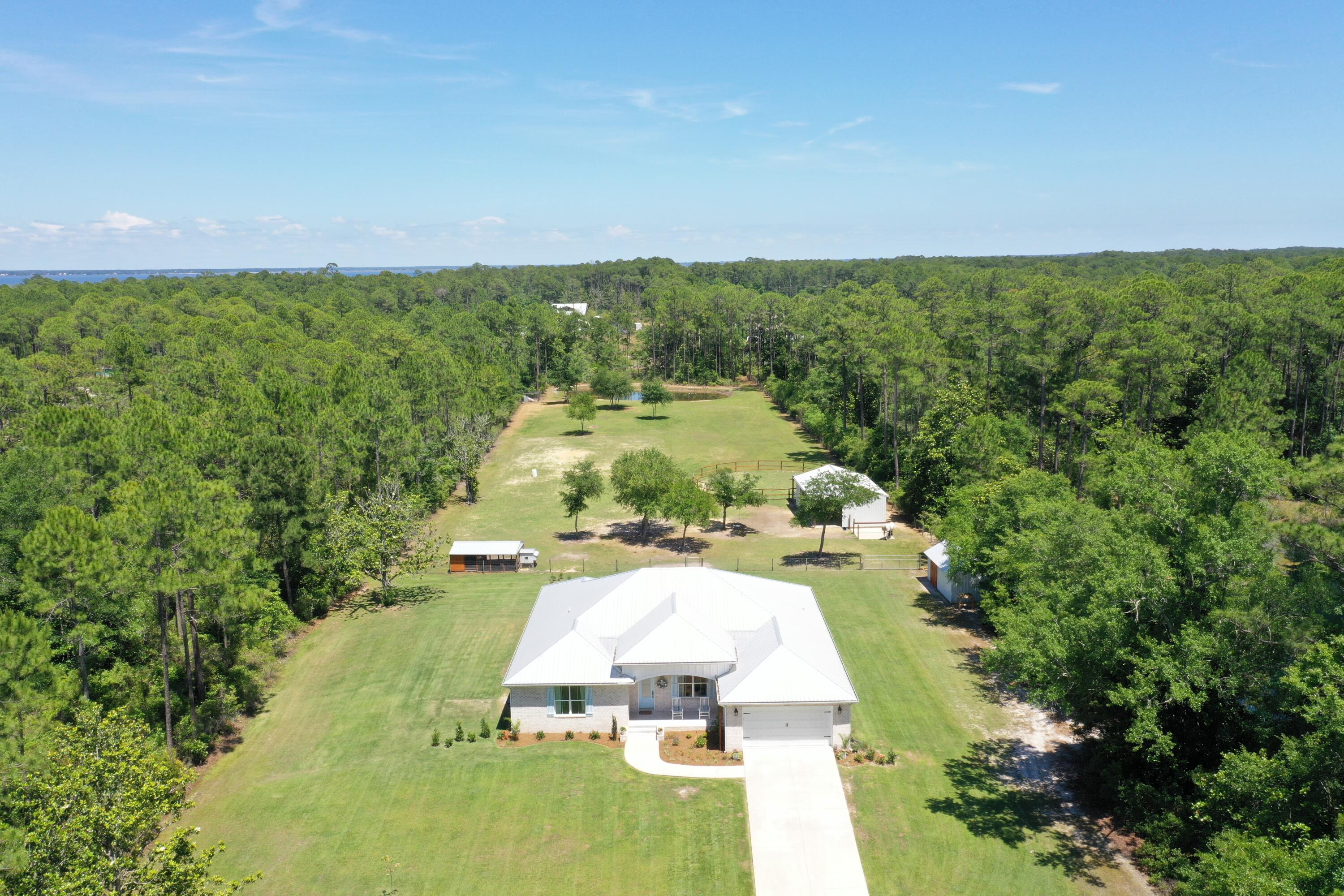 Experience coastal country living at its finest with this exceptional custom-built equestrian estate just minutes from the white sands beaches. Nearly 5 private acres nestled behind a gated entrance with automatic openers, this property welcomes you home with a long shaded driveway, offering both privacy and a peaceful estate feel from the moment you arrive. The estate blends modern luxury, durability, and fully equipped farm living. 

Designed with quality construction in mind, the home features upgraded 2x6 exterior framing, a metal roof, impact-rated windows, whole-house water treatment system, and built on a concrete stem wall for long-term comfort and peace of mind. 
Inside the nearly 3,000sf home you'll find 5 spacious bedrooms, each with walk-in closets, and 3 full bathrooms finished with elegant quartz countertops throughout. The open-concept layout offers engineered wood flooring, oversized 8-foot doors throughout the home, and a beautifully designed kitchen complete with a walk-in pantry, generous entertaining space, and a stylish wine nook with built-in wine fridge. Outside there is an outdoor shower to rinse off after a day at the turquoise beach.

The property is perfectly suited for hobby farming, equestrian living, enjoying the tranquility and beauty of the outdoors or simply turn the barn into enclosed storage for boats, cars, or other recreational activities. Additional Features include:
3-stall horse barn with wash rack, tack room, automatic waterers and storage area (or converted into boat/recreation storage).
Chicken coop with enclosed run
Dedicated duck enclosure near the estate pond
Outdoor storage/yard building

Expansive open acreage with room to roam and fenced pasture for horses, furry friends to run, or other livestock.
Additional highlights include a 2-car garage, serene private pond, mature landscaping, and the rare combination of beach and bay proximity with functional farm amenities. The public boat launch is less than one mile away and the property offers ample space for parking boats and recreational vehicles.

There is ample space to design a luxurious estate pool with ambiance and privacy.

This one-of-a-kind estate offers the ideal blend of luxury living, rural charm, and coastal convenience.

Owner is a L.R.E.A.
