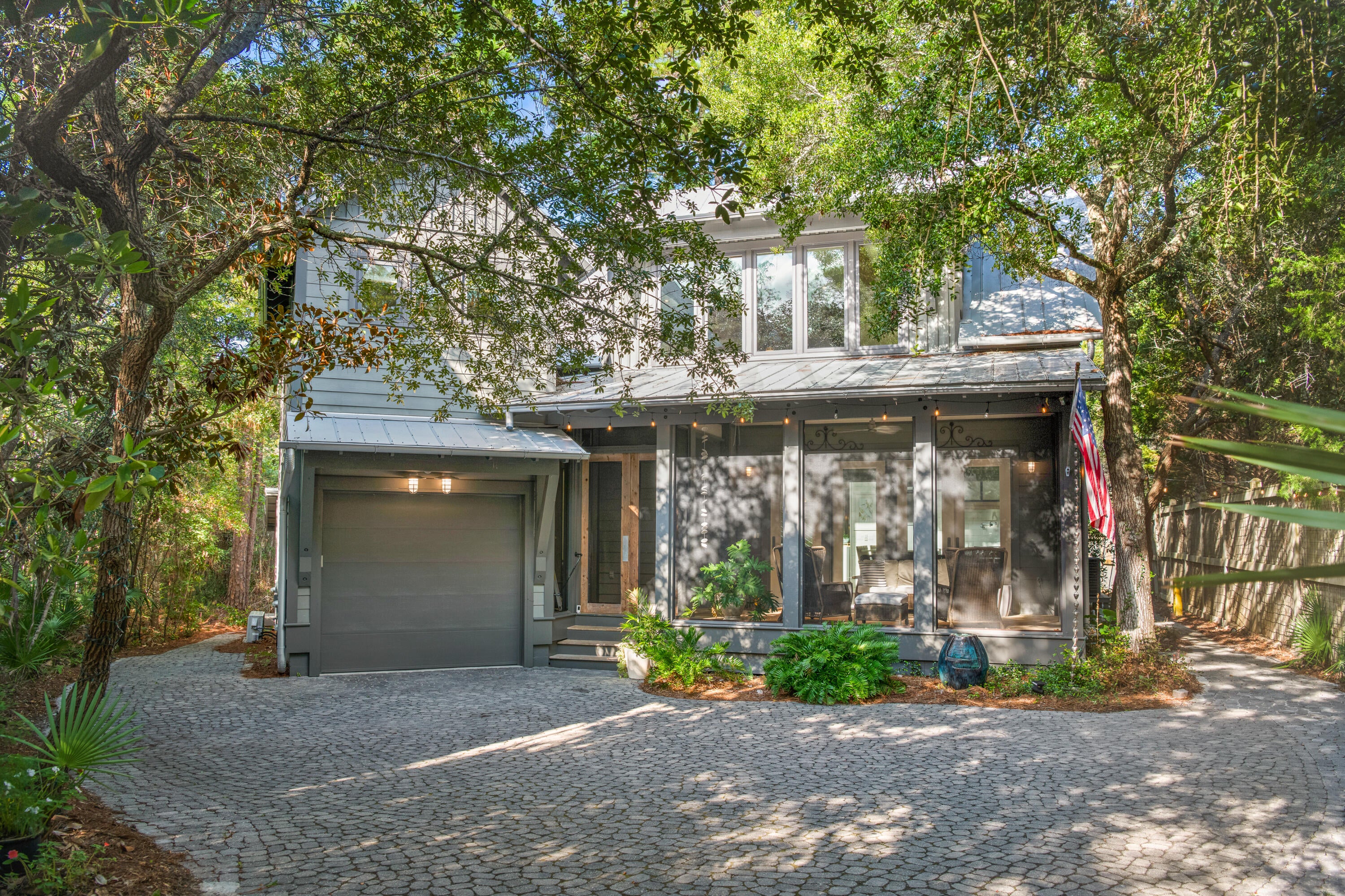 Located in the Hammocks of Seagrove, this 3,400-square-foot home sits on the neighborhood's largest lot. The gated community offers added privacy, and the secluded home abuts Watercolor & the canal leading to Western Lake. A long driveway leads to an inviting front porch. Inside, large windows fill the open kitchen & living area with natural light. French doors open to a screened porch & a private side deck surrounded by mature magnolias, live oaks, & pines. The kitchen features a Sub-Zero refrigerator, six-burner range, full-size & convection ovens, a 11' island, ice maker & a walk-in pantry with an additional refrigerator. The first-floor primary suite includes two large walk-in closets & a bathroom with dual vanities, spacious shower, soaking tub & bidet. Upstairs, a loft overlooks the great room & connects to three bedrooms & two additional baths. The carriage house includes a kitchenette, bedroom, sitting area, & full bathroom. It is the only home in the community with both a garage & separate guest suite.The home has 5 bedrooms & 4.5 bathrooms in total. Residents enjoy two community pools, & this property offers room for a private pool. Additional features include reclaimed wood floors & beams, shiplap walls, central vacuum, whole-house water filtration, two outdoor showers & a storage building. Never used as a short-term rental, the home has been well maintained. Seaside, Watercolor, dining, shopping, trails & several beach accesses are a short walk /bike ride away.