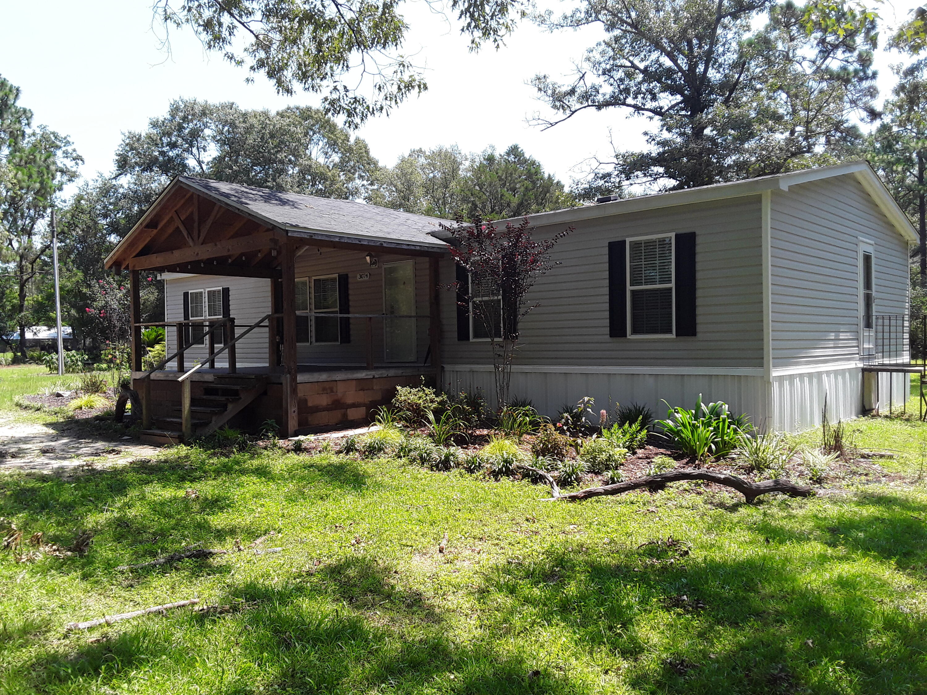 This is a ''Gardener's Paradise'' on this 3.45 acre property with a double entry gate and fully fenced.  Beautiful grounds with a variety of trees, assorted exotic flowers and bushes, grapes and blueberries.  This Scotbilt house with an 18' x 12' covered porch has many upgrades:  all drywall, tray ceilings, crown molding, no carpet, Frigidaire appliances, large island, walk-in shower, double sink vanity, garden tub and a Whole House Ventilation System.  The property grounds has so much to offer:  An outbuilding with a finished  Hardi-board exterior, metal roof and wood covered porch.  There are 3 interior rooms with insulated walls but not finished out - loads of possibilities. There is a 15' x 26' garage/workshop with rollup door and entry door.  For the gardener you will love this oversized greenhouse - all equipped with vented windows, fan, fluorescent lights, water and shelving.  That's not all - in the rear of the property is an area for gardening, grapevines and blueberries.  From the moment you step on this property you will love its beauty.  Walk the grounds and look for all the beautiful floral surprises.  There is a fire pit/burn area in the rear.  In addition, there is a Triton container with an attached Lean Too.  Container is clean inside and great for storage.  This home and property is move in ready and being sold AS-IS.