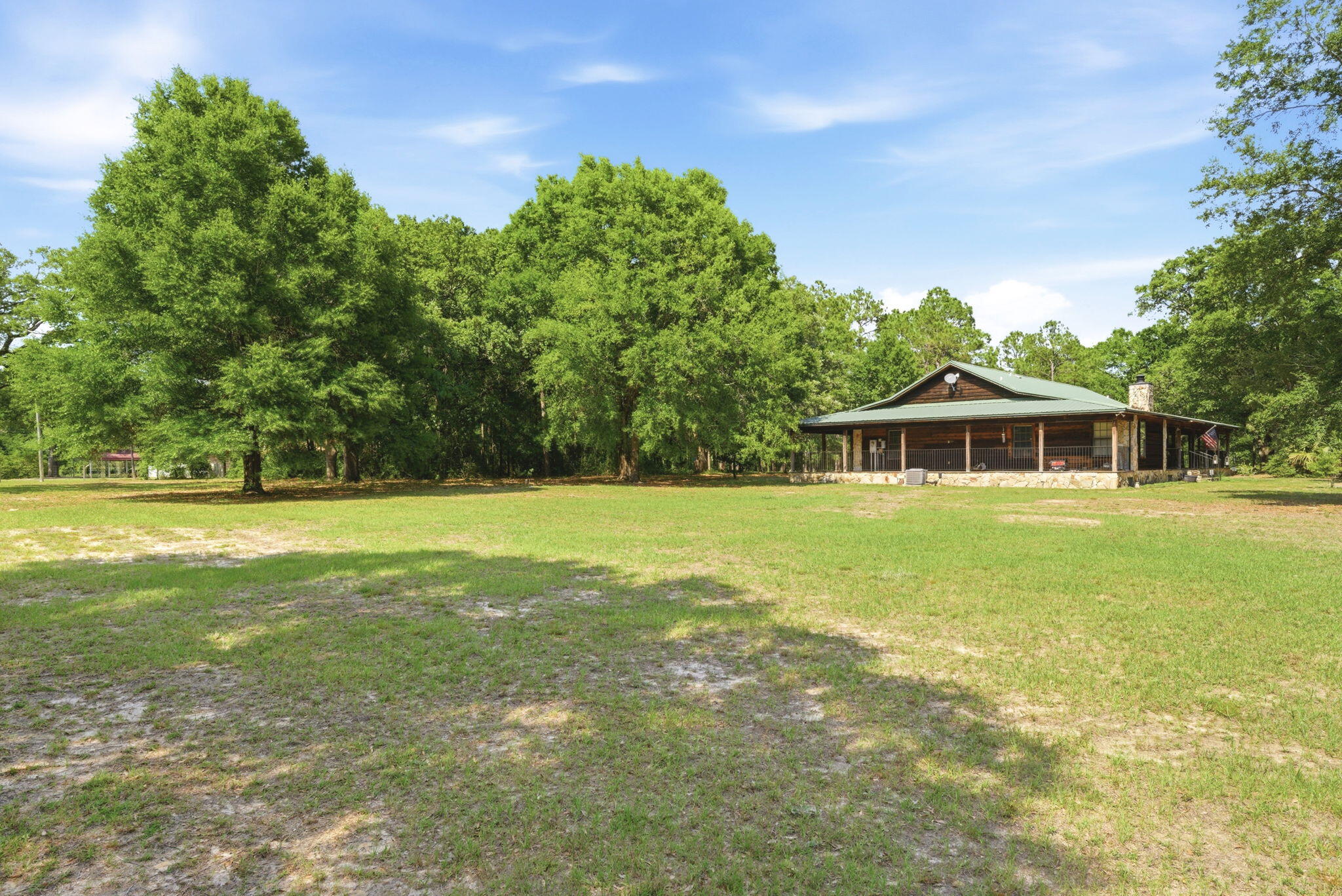 Enjoy peace and tranquility on six breathtaking acres, completely fenced, shaded by majestic heritage oak trees and surrounded by beautifully manicured green lawns. Relax on the expansive wraparound porch of this charming cedar plank home while taking in the beauty of your private retreat. Conveniently located with easy access to I-10, this property offers the perfect blend of country living and accessibility. Inside, the spacious floor plan is highlighted by a stunning stone fireplace that serves as the focal point of the main living area, accented by the tongue and groove vaulted ceiling, creating a warm and inviting atmosphere. The large open kitchen is ideal for entertaining, allowing you to stay connected with family and guests while preparing meals. The oversized master suite is truly exceptional, featuring a generous walk-in closet, a separate shower, and a relaxing jacuzzi tub for a spa-like experience. Step outside to find a large workshop complete with multiple electrical outlets and roll-up doors, making it perfect for storage, hobbies, or projects of any kind. Horses are welcome, giving you the opportunity to fully enjoy the acreage and lifestyle this unique property provides.