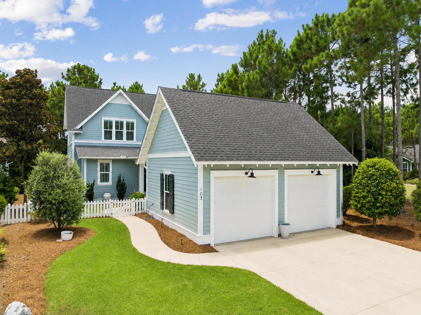 Tucked beneath the pines on a picket-fenced homesite in Watersound Origins, 103 Jack Knife Drive offers easygoing Florida living with timeless charm. This 3-bedroom, 2.5-bath home delivers classic curb appeal along with a detached two-car garage with gooseneck lighting, while inside you'll find a bright, thoughtfully finished interior. Wide-plank hardwood floors, shiplap accent walls, wainscoting, crown molding, and plantation shutters run throughout the main level, where the open living room flows to a dining area anchored by a beaded chandelier and a crisp white kitchen with quartz counters, subway tile, gas range, stainless appliances, oversized island seating, and a lighted glass-front bar/butler's nook. The main-level primary suite features a shiplap feature wall and a spa-style bath with double quartz vanity, soaking tub, and separate tiled shower. Upstairs offers two additional bedrooms plus generous walk-in closets and walk-in attic storage. Outdoor living shines: a screened porch with hanging bed swing and shiplap ceiling opens to an expansive paver patio with fire pit and café lighting, all wrapped by a white picket fence with green space beyond. Residents of Watersound Origins enjoy the Village Commons resort-style pool, fitness center, events lawn, miles of nature trails, Origins golf, and Lake Powell access, all just minutes from 30A's beaches, dining, and the Watersound Town Center.