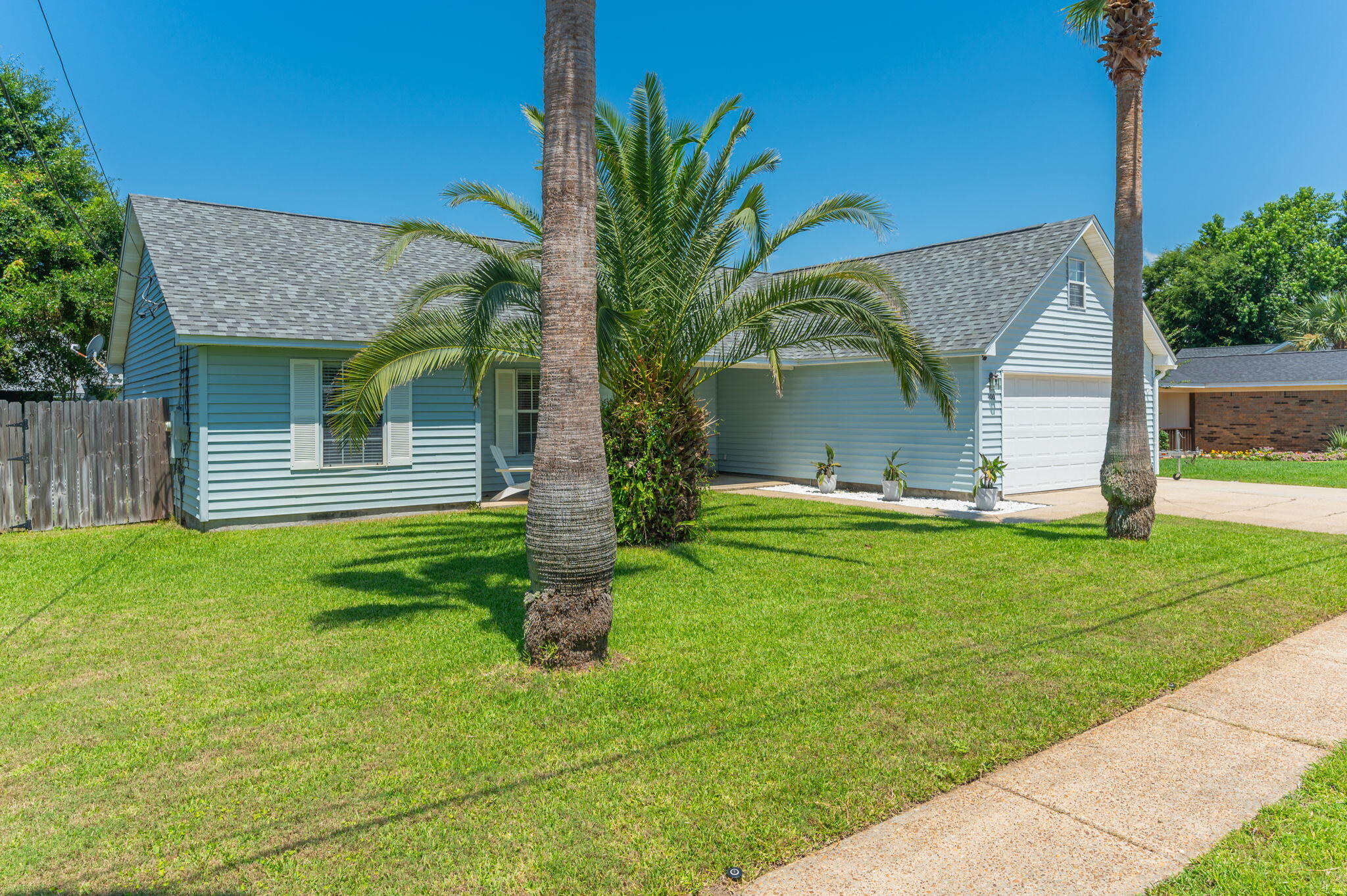 Bring your boat to your coastal oasis at 400 Primrose Circle! Nestled in a prime location with convenient proximity to Destin's iconic HarborWalk Village and Crab Island, this charming ranch-style home beautifully balances modern updates with coastal flair. From the moment you arrive, the vibrant palm tree, manicured green lawn, and extended driveway leading to a spacious two-car garage radiate welcoming curb appeal.
Step inside to find a bright and open floor plan featuring easy-to-maintain solid surface floors throughout and vaulted ceilings that amplify the home's spacious feel. The living room serves as the heart of the home and flows seamlessly into the kitchen, which is fully equipped with classic wood cabinetry, sleek dark granite countertops, and premium stainless steel appliances. A functional breakfast bar setup overlooks the dining and living areas, ensuring the chef is always part of the conversation.
The home features beautifully modernized bathrooms designed with high-end style in mind. One bathroom boasts a crisp white vanity with sharp black hardware and ample cabinet storage, while another showcases an on-trend charcoal grey vanity paired with luxurious brushed gold hardware, a matching gold-framed mirror, and tiled tub-shower surrounds.
The indoor living spaces transition effortlessly to a massive, fully fenced backyard. This sprawling green lawn offers unlimited potential, whether you dream of installing a custom pool, letting your pets roam freely, or hosting weekend barbecues on the paved patio. A detached storage shed provides the perfect spot for your lawn equipment or beach gear. Roof (2024), HVAC (2021), HWH (2012).  Don't miss the opportunity to own a slice of paradise near the coast. Schedule your private viewing today!