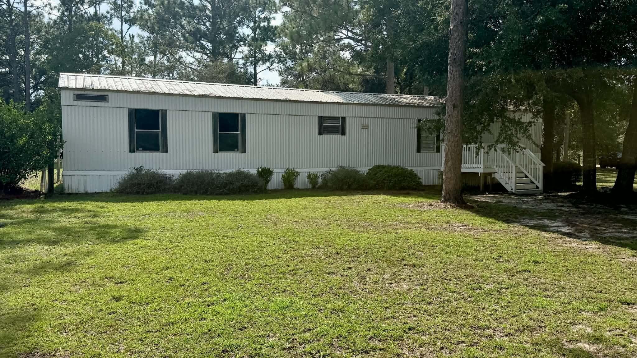 Situated on a 1.20-acre perfect corner lot, this property offers plenty of space both inside and out. The home offers a split floor plan with 2BR/2BA, large open living room and kitchen with tons of cabinet space and all the appliances included.  Major updates provide added peace of mind, including a 4-year-old heavy-metal roof designed to help protect against damage from falling tree limbs or storms. The HVAC system is also approximately 4 years old and has 6 years remaining on its warranty. Another valuable feature is underground power service to the home, eliminating the worry of tree branches taking down overhead power lines. Conveniently located close to town while still offering the feel of a spacious country setting. Enjoy the privacy and beauty of the property, complete with established blueberry bushes, a large area for a garden, and tons of room for outdoor play.  If you're looking for room to spread out, desirable updates, and a convenient location, this property is ready to welcome you home! Mobile home has been moved to its current location from a previous location so PLEASE READ - conventional financing with 5% down available.