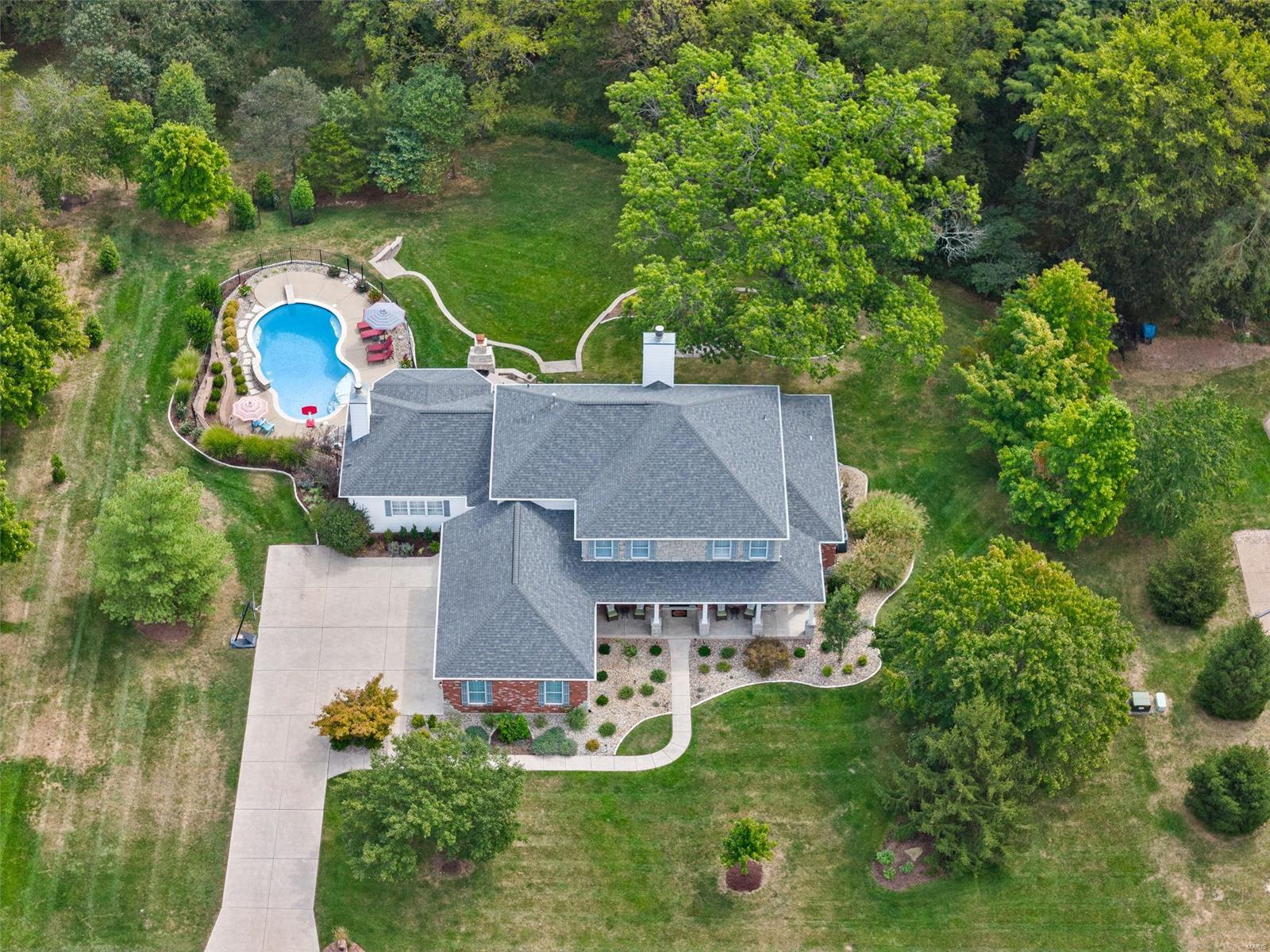 This gorgeous 1.5-story home with over 6,000 sq ft of living space has the yard of your dreams! Backing to woods that allow for wonderful privacy, it includes a landscaped heated pool w/diving board, waterfall & fun pool room, multiple patio spaces, stone fireplace & deck. Beautifully updated interior offers livable luxury, including the finished walk-out lower level that features a rec room w/fireplace & wet bar, bonus room, & private bedroom suite teens or visiting guests will love. Gather on the main level in the 2-story great room w/soaring Palladian windows overlooking the woods or the hearth room w/bay window pool views. Well-appointed kitchen has granite counters, LED undercabinet lighting, expansive breakfast bar, double wall ovens & gas downdraft cooktop. California Closets finishes in the primary suite walk-in & laundry room. All 5 bedrooms have walk-in closets & private bath access. Outstanding home built for entertaining & a casually elegant lifestyle! See it today!