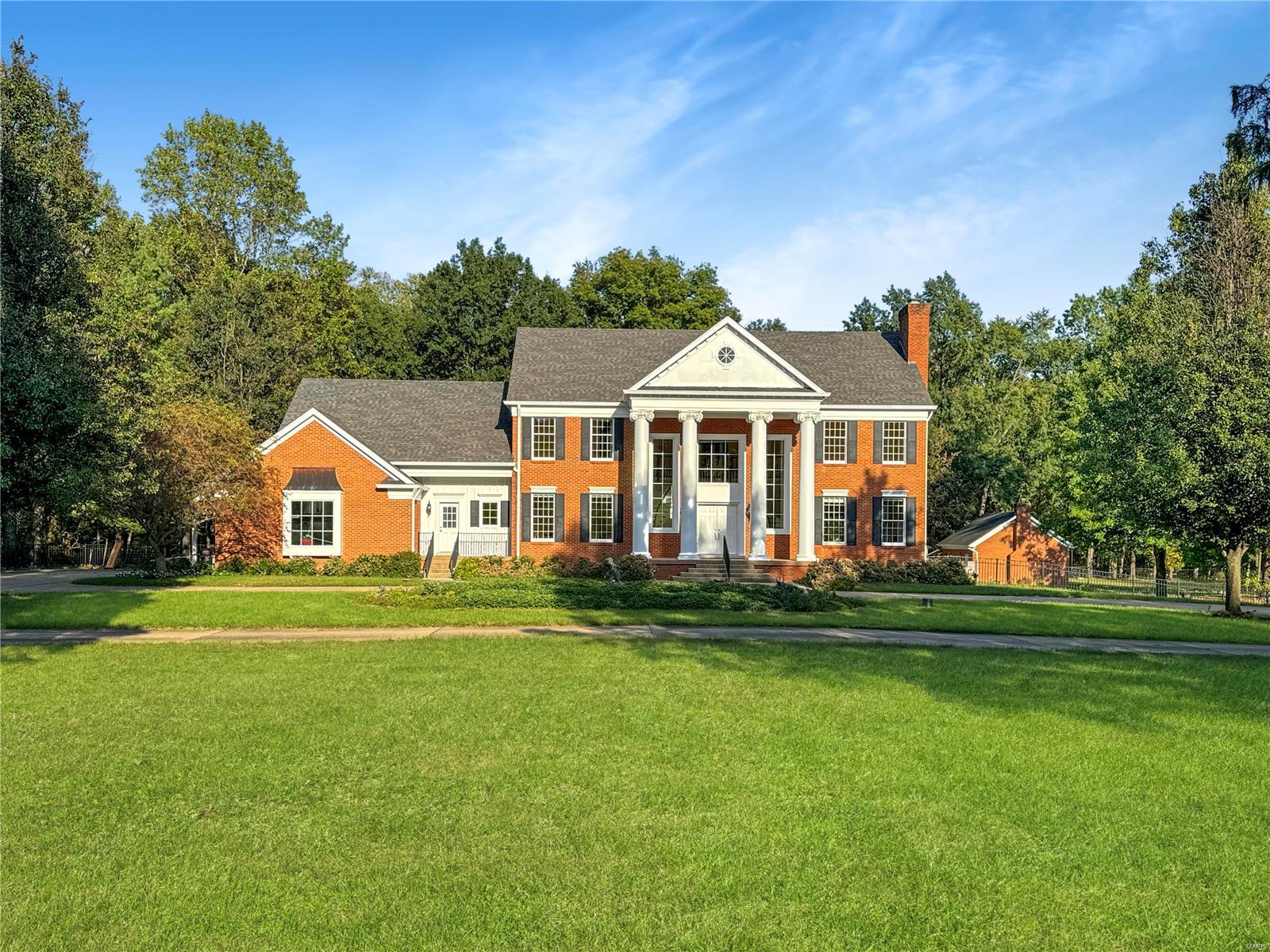 This stunning Neoclassical home, set on 11.23 private tree-lined acres backing to a creek, is perfect for the holidays with an asphalt and concrete circle drive. A grand two-story porch with columns that greet you, leading into a breathtaking entryway with two curved staircases. The main level offers a living room, dining room, library/office, den, family room & a large custom kitchen with a breakfast area that opens to a patio overlooking the private backyard. Upstairs, the primary suite features a fireplace, jetted tub, & walk-in closet, & 2nd  Suite and 2 additional bedrooms with hall bath. The lower level includes a bar, game room, rec space, office, and storage. This move-in-ready gem is perfect for holiday gatherings. Freshly painted inside & out. 2018 updated septic system, Aluminum fencing backyard, sprinkler system, & solid hickory floor, 2019 replaced front landscaping, added bushes & trees, 2020 added greenhouse, & Updates on HAVC replaced 2 & updated components on 1. Hurry!
