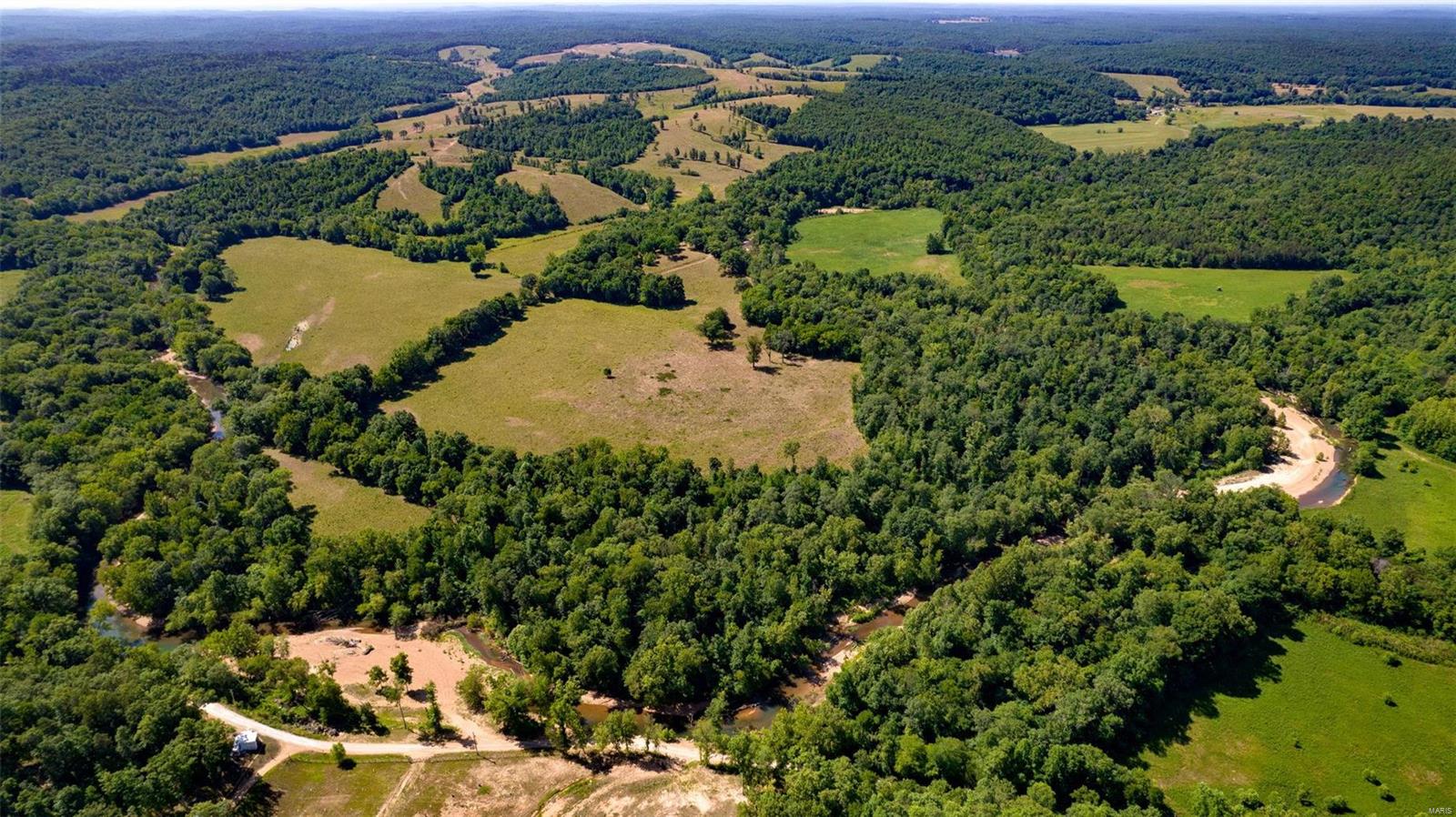This is a 1710 +/- acre property located in Lowndes MO Wayne County and is a rare find in this area. It offers an exclusive turn-key cattle ranch, shop with living quarters, barns, storage, and several cattle pens.  It is an income producing property that offers hunting, year-round water, and breathtaking views. The property is housed with more than 112,000 feet of fencing. The cattle capacity is approximately 300 head and hay production is between 800 and 1200 bales annually. Enjoy great bass fishing on 1.5 miles of Bear Creek. The ranch has 19 ponds and 50% of it is pasture and 50% is mixed timber/creek bottoms. The property offers hunting ground that has generated many proven successful hunts. It has 11 deer blinds and numerous food plot areas and generates $20-$25,000 dollars annually in hunting trips offered. There are also a number of bluffs and caves located on the property. The home on the property includes 4 beds/3 baths and is adorned with high-end finishes.