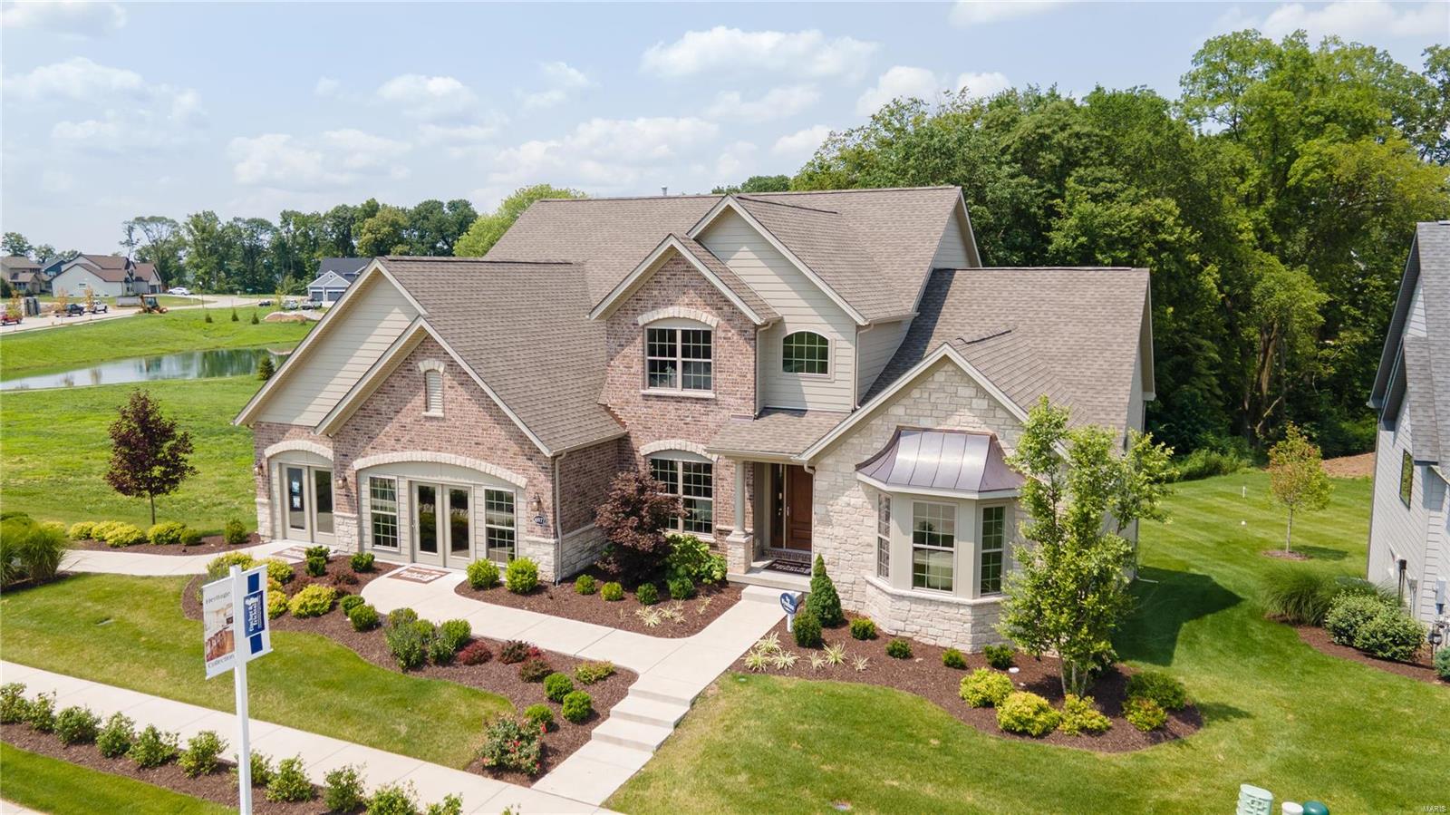 Spectacular display home with amazing finishes and todays desirable features! Residents will enjoy a 26 AC lake, playgrounds, walking trls and more in a fantastic location. This Executive Fischer and Frichtel display has 4 BD, 3.5 BA, 4,037 s/f, 3 car garage and a step up Bonus Rm. The ext is exquisite with Hardie siding, brick with stone accents, arch shingles, prof landscape, lawn irrig, walkout lot backing to wooded common ground and a 14x12 composite deck. Features inc 9 ft clngs with 11 ft in the Grt Rm, beamed Grt Rm clng, Hearth Rm with gas FP, gourmet Kit with 42 inch cabinets, crown molding, Quartz countertops, large island, chimney hood, 6 brnr gas cooktop, drawer micro, refrig, dbl oven, tile backsplash, W/I pantry with cust shelving, cooks bath, butlers pantry, hardwood flrs, Owners Suite with wood inlaid clng, spa-inspired bath, free standing tub, cust shower, large W/I closet, one bdr has a private bath, jack-jill bath, tall bsmt pour, 8 ft int doors and more. Its a WOW!
